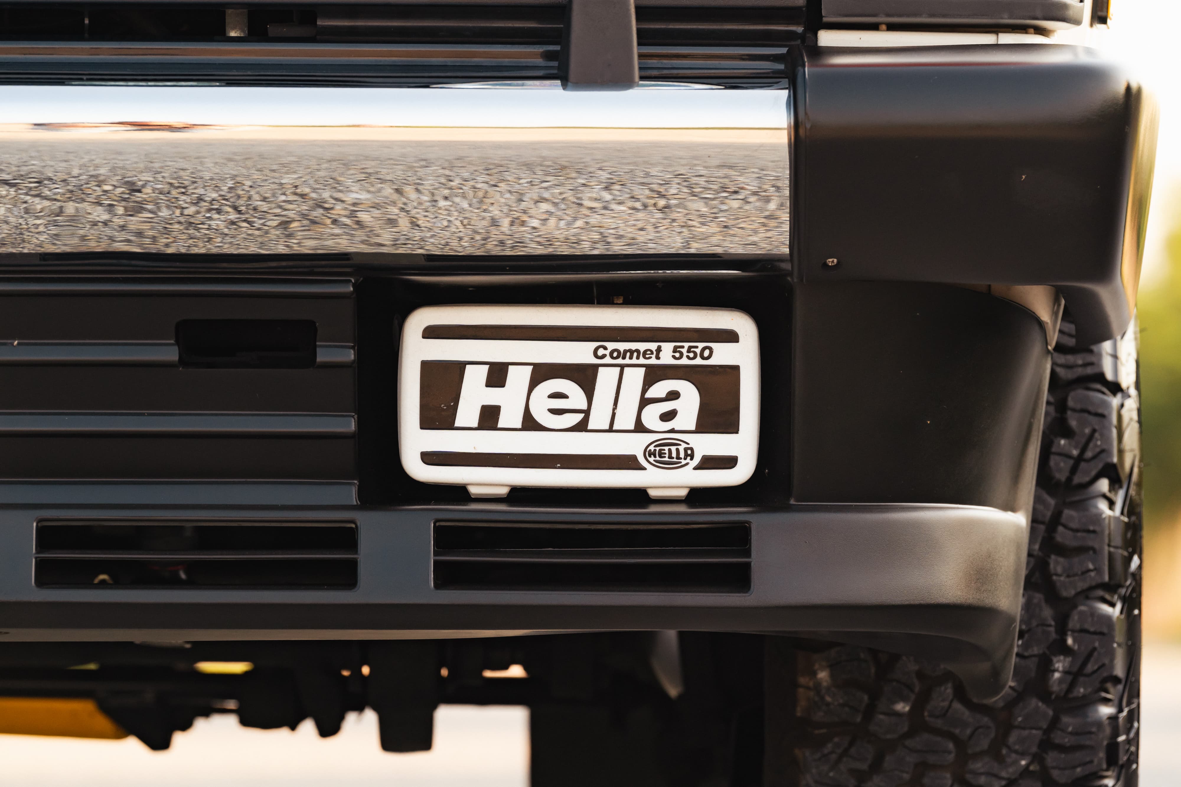 Front bumper of a white 1995 Land Rover Range Rover County with Hella Comet 550 fog lights.