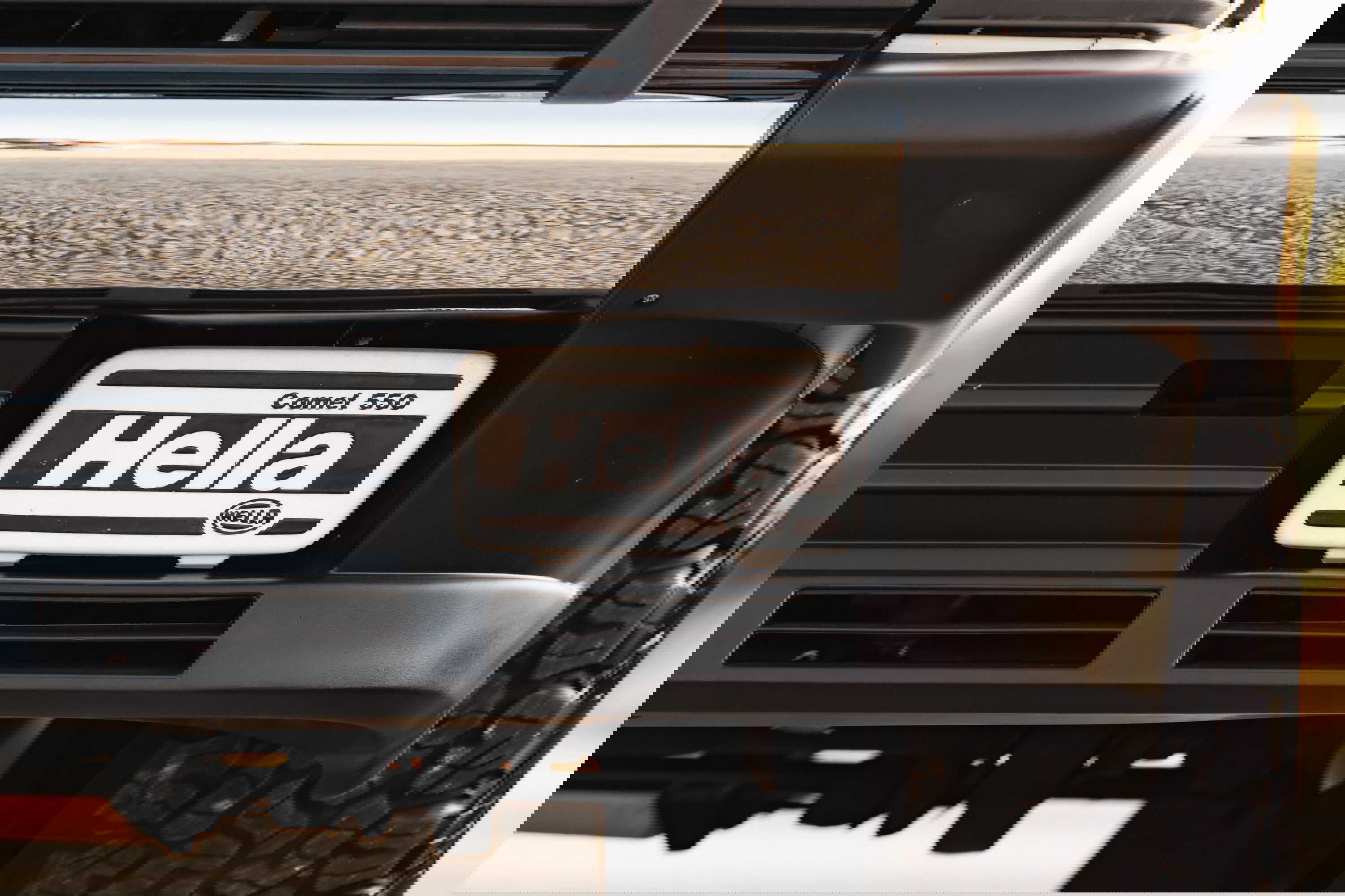 Front bumper of a white 1995 Land Rover Range Rover County with Hella Comet 550 fog lights.