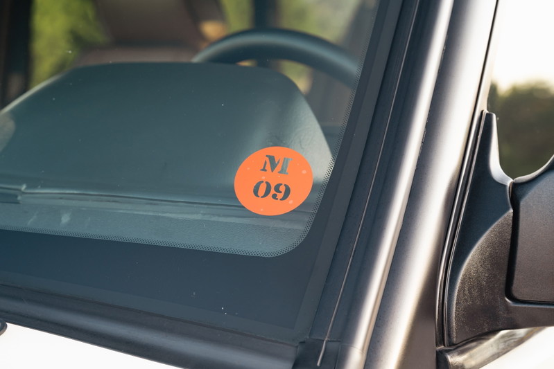 Orange inspection sticker with M 09 on the windshield of a white 1995 Land Rover Range Rover County.