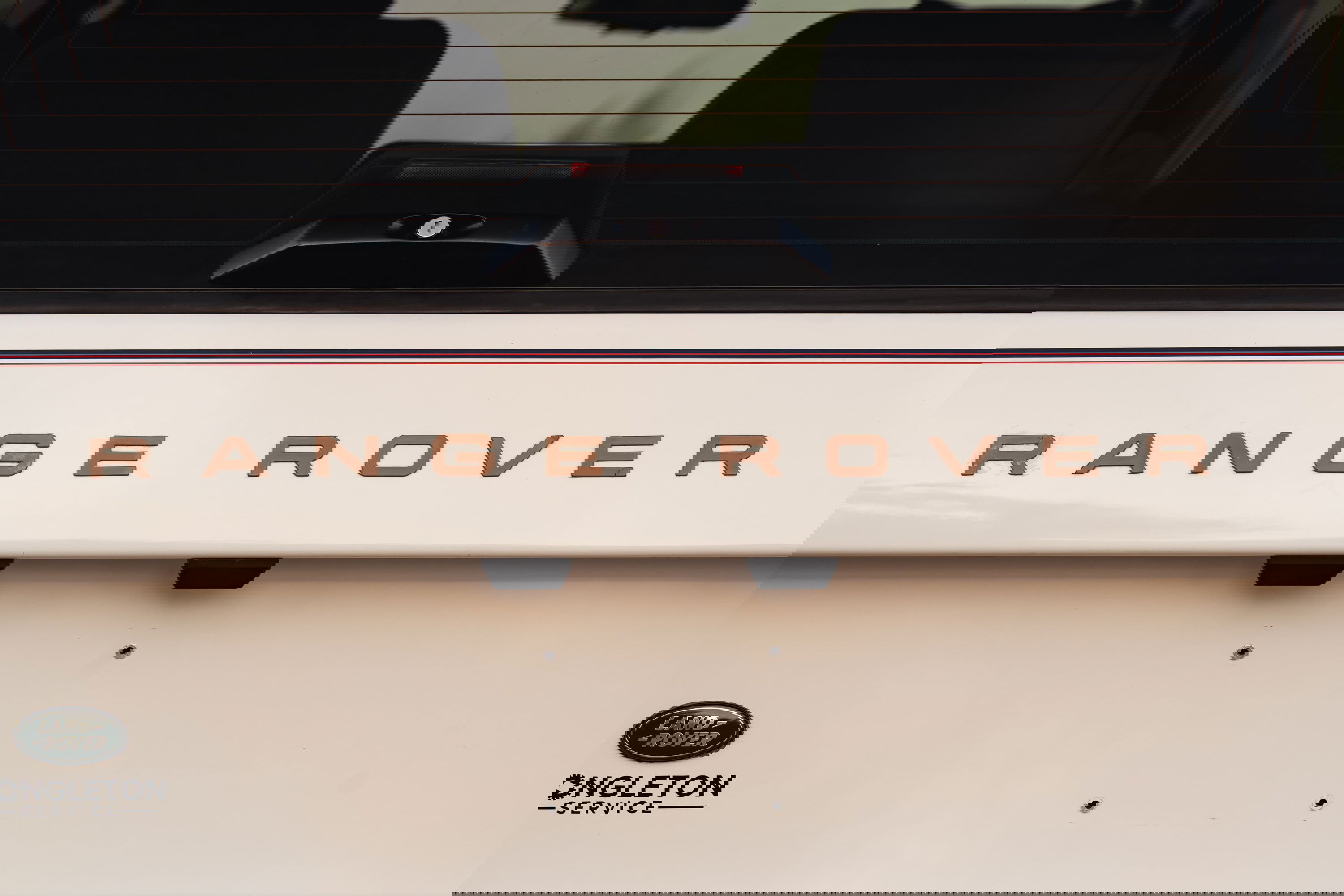 Close-up of a white 1995 Range Rover County tailgate with bronze &quot;RANGE ROVER&quot; badging.