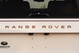 Close-up of a white 1995 Range Rover County tailgate with bronze "RANGE ROVER" badging.