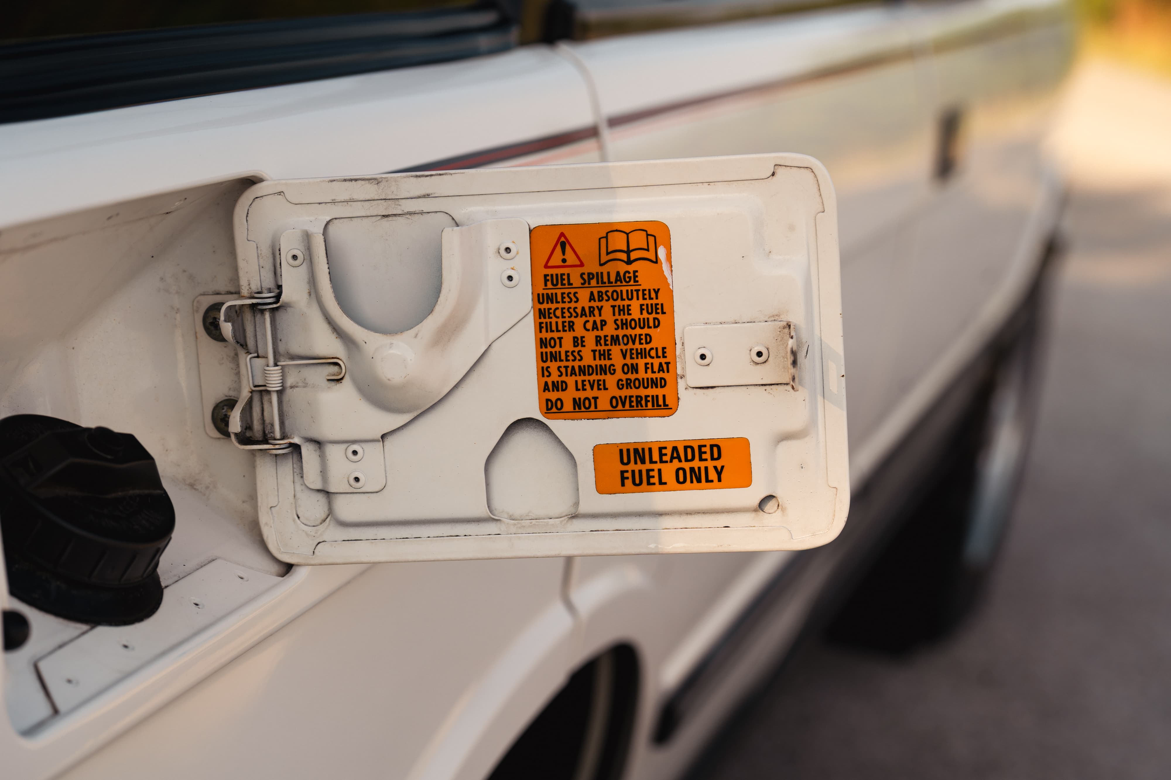 White 1995 Range Rover County fuel door open, showing warning labels.