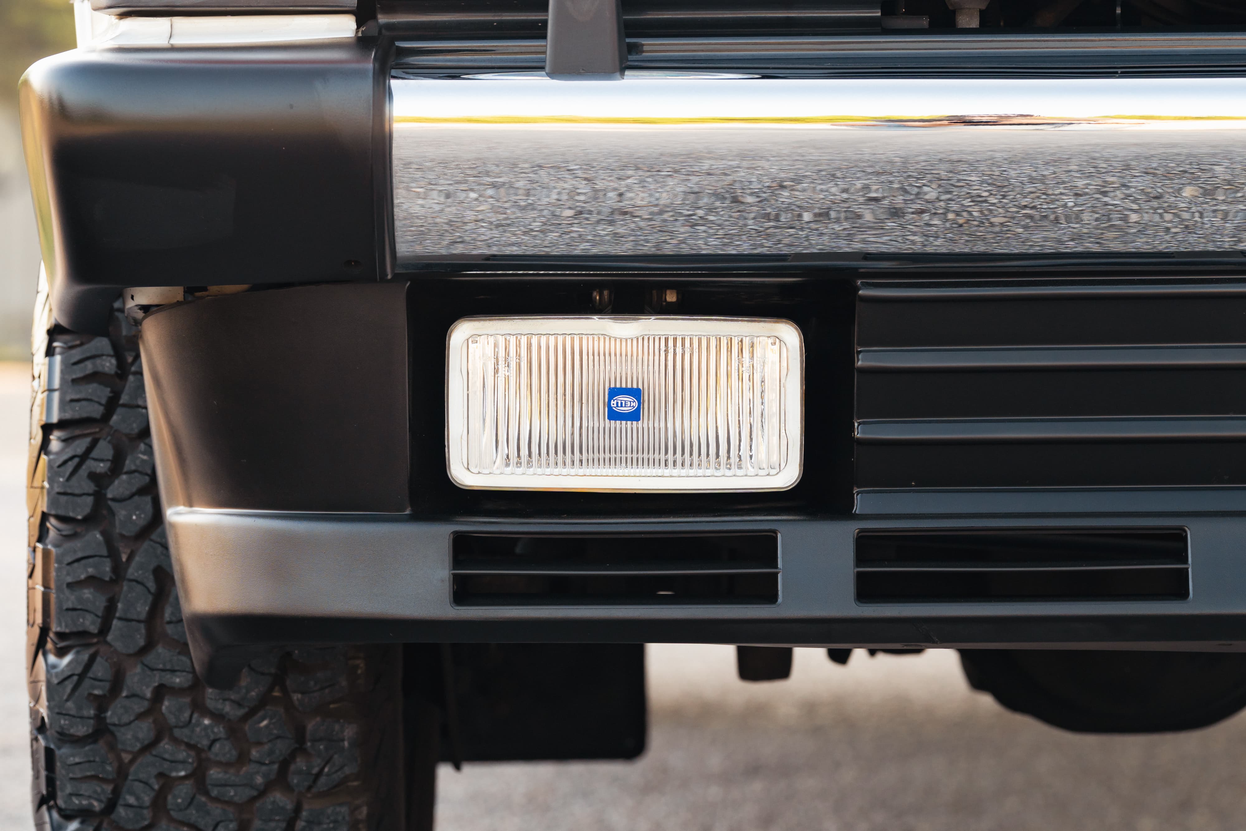 Close-up of a white 1995 Land Rover Range Rover County front bumper with HELLA fog light.
