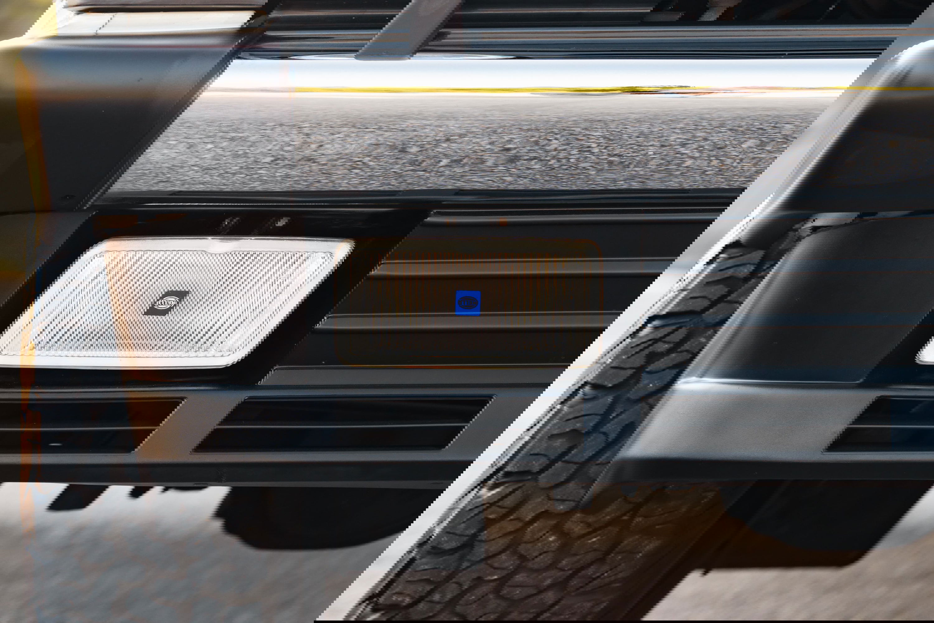 Close-up of a white 1995 Land Rover Range Rover County front bumper with HELLA fog light.