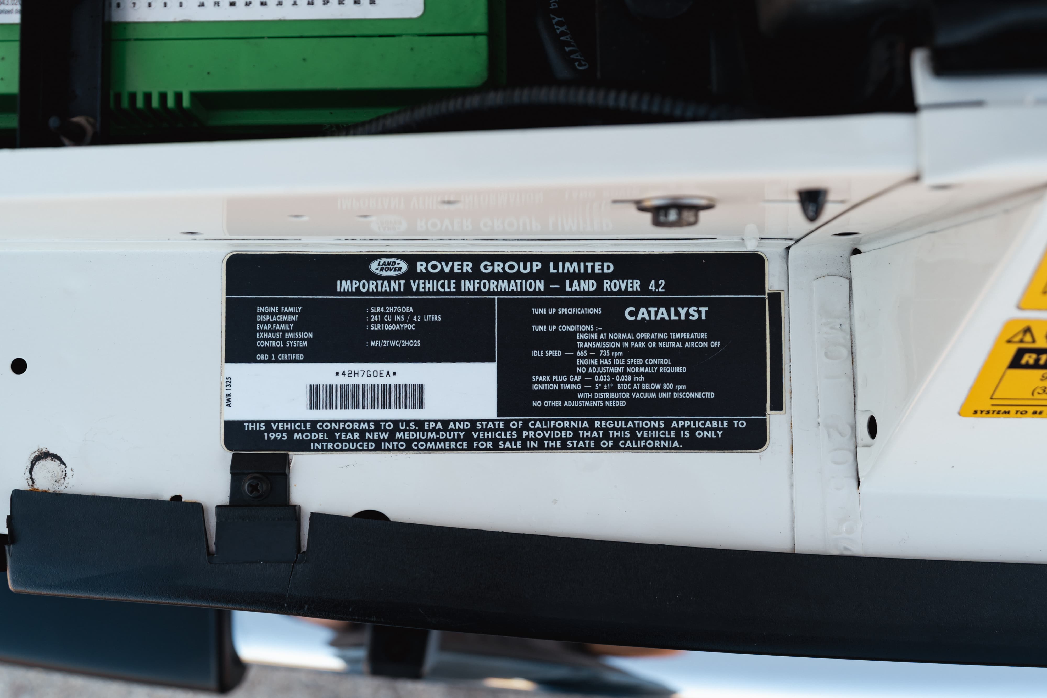 Close-up of the VIN plate and emissions sticker on a white 1995 Land Rover Range Rover County.