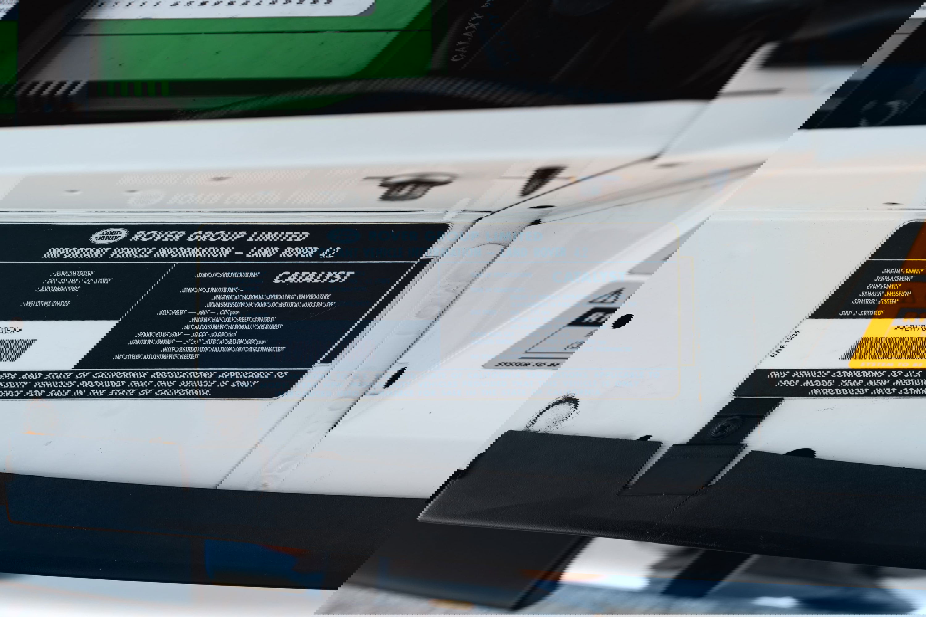 Close-up of the VIN plate and emissions sticker on a white 1995 Land Rover Range Rover County.