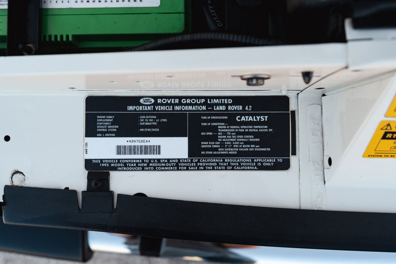 Close-up of the VIN plate and emissions sticker on a white 1995 Land Rover Range Rover County.