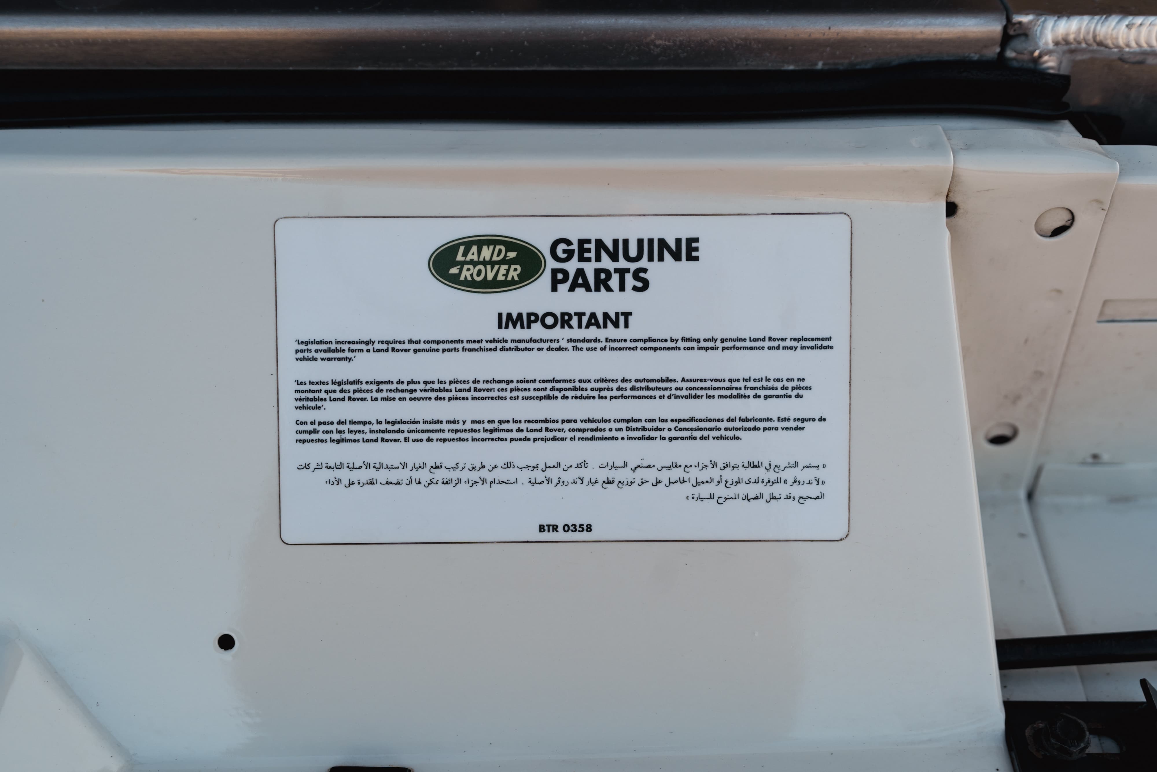 Close-up of a sticker on a white 1995 Land Rover Range Rover County with &quot;Genuine Parts&quot; text.