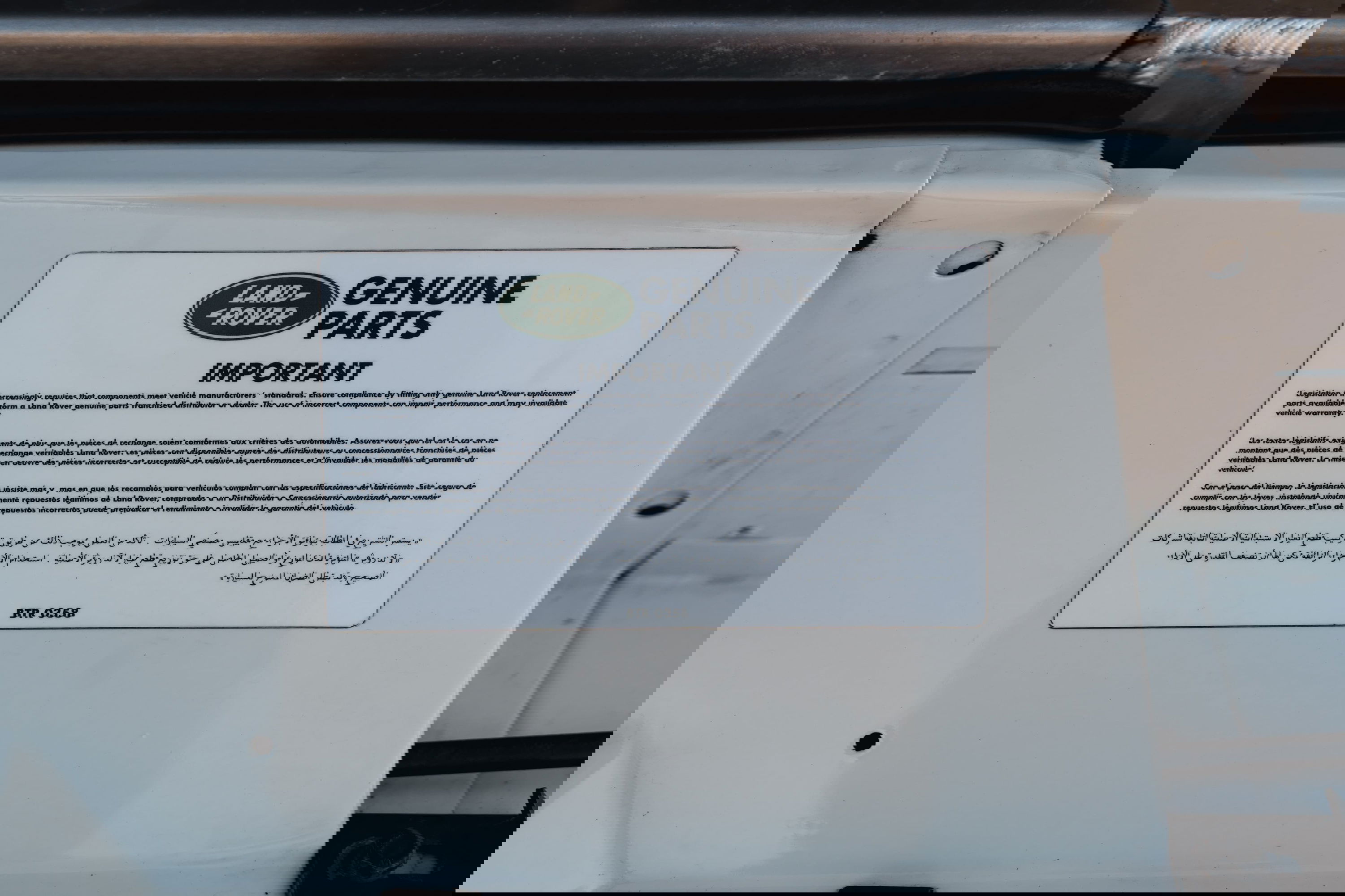 Close-up of a sticker on a white 1995 Land Rover Range Rover County with &quot;Genuine Parts&quot; text.