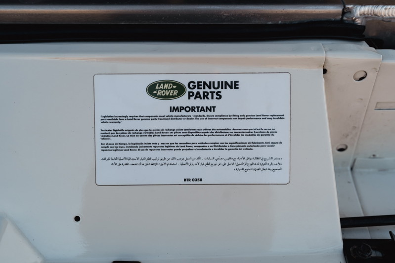Close-up of a sticker on a white 1995 Land Rover Range Rover County with "Genuine Parts" text.