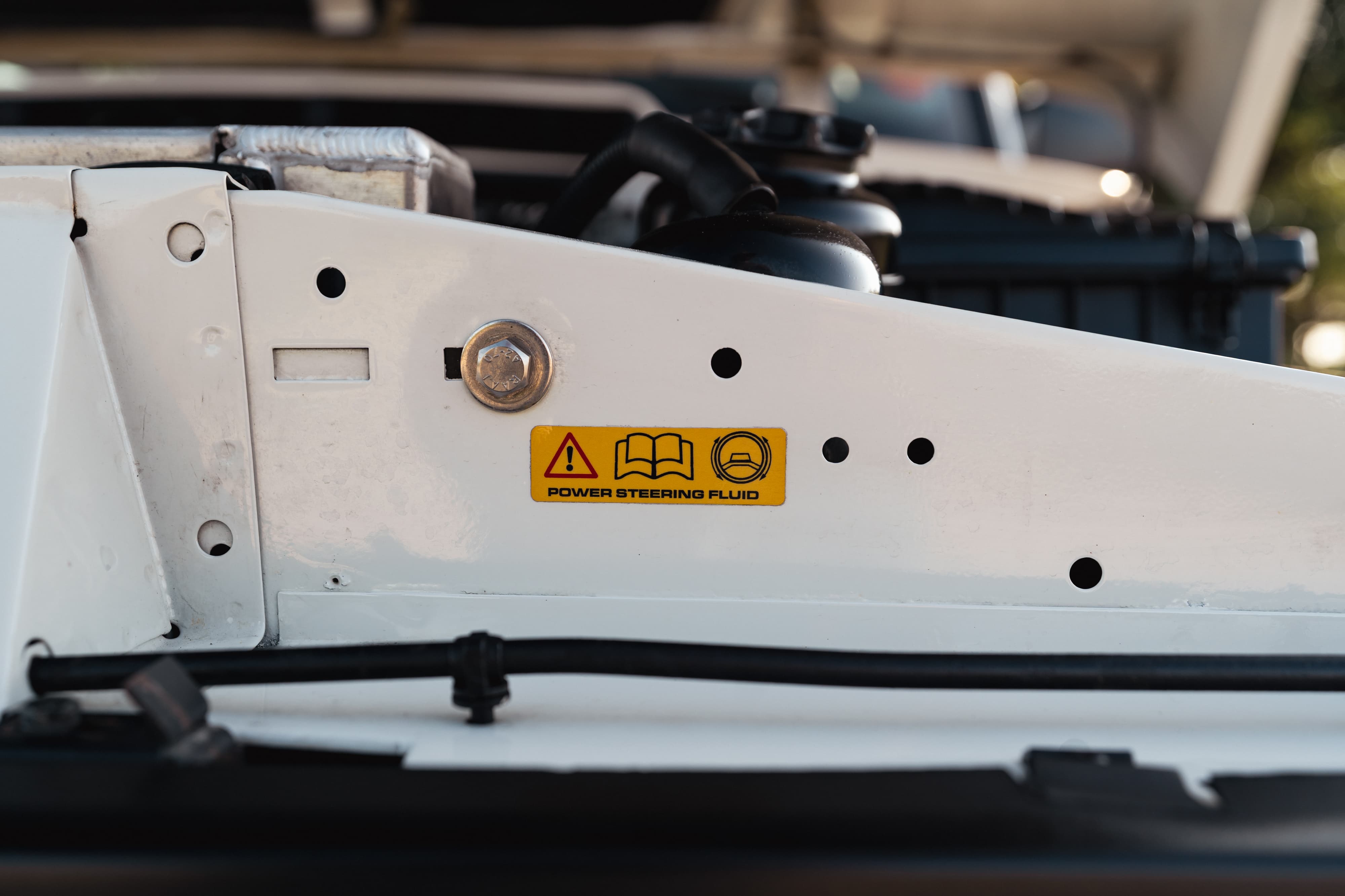 Close-up of a white 1995 Land Rover Range Rover County engine bay with a power steering fluid warning sticker.