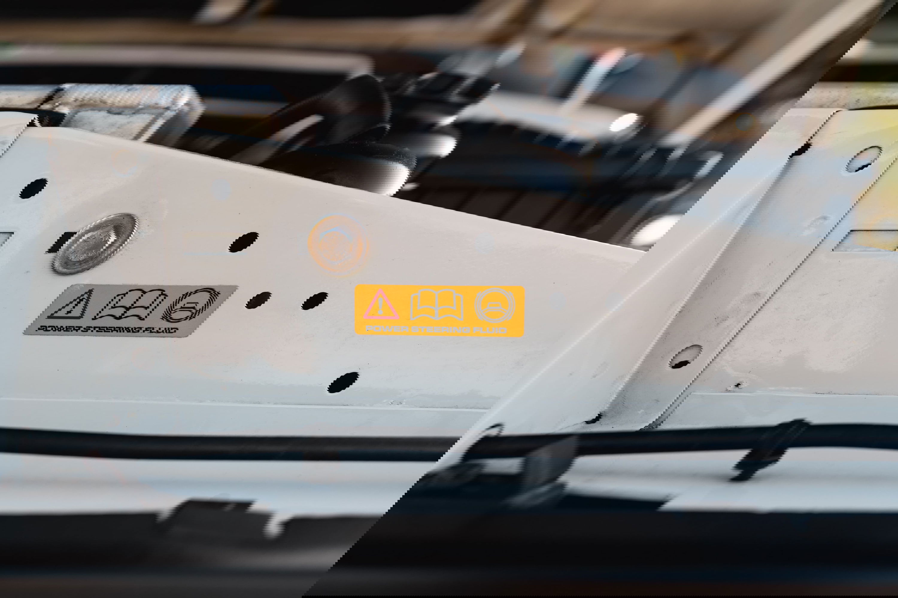 Close-up of a white 1995 Land Rover Range Rover County engine bay with a power steering fluid warning sticker.