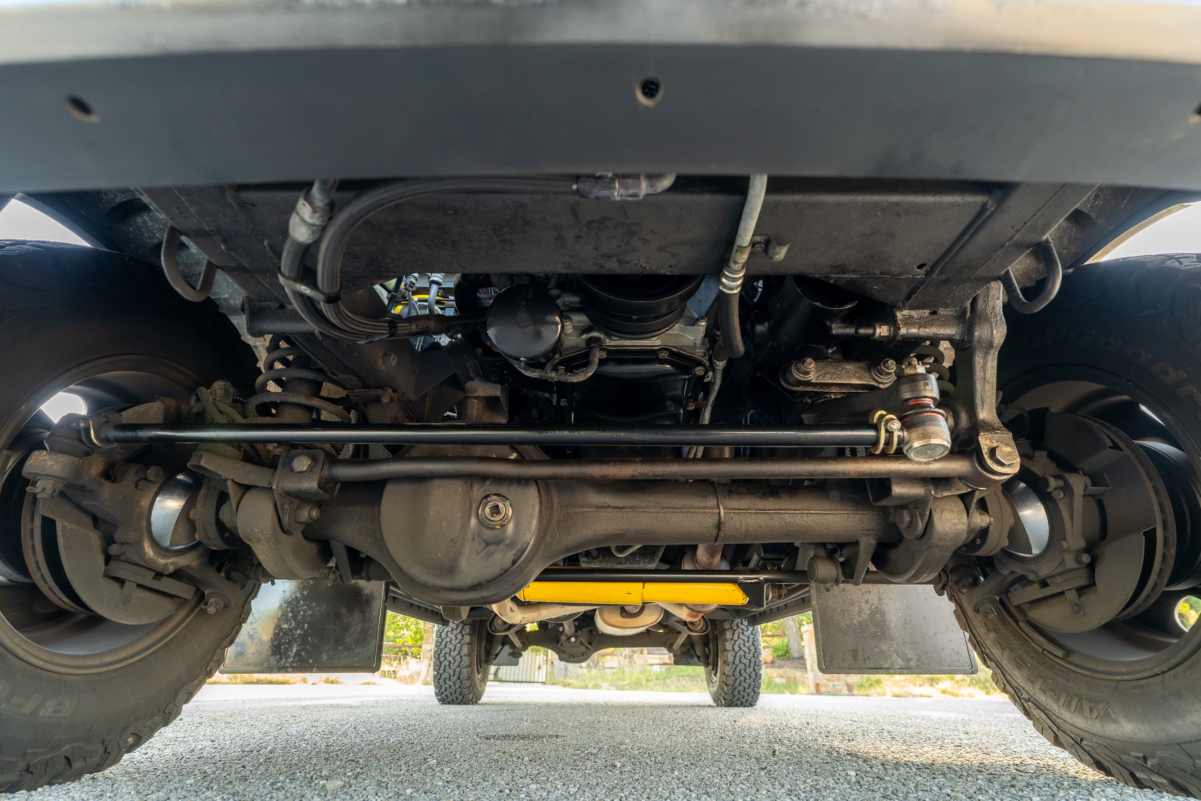 Underside of a white 1995 Land Rover Range Rover County showing suspension and drivetrain.