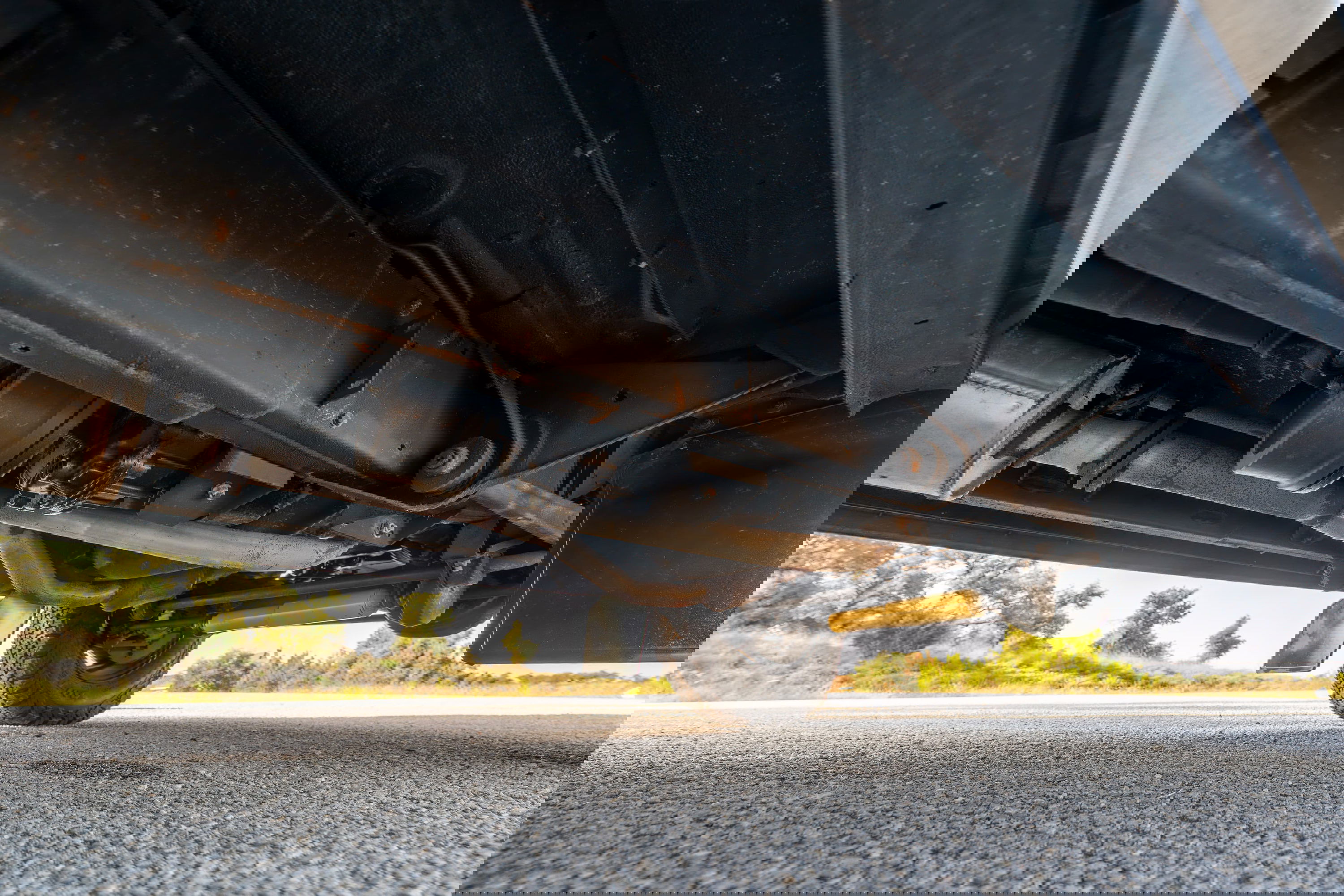 Undercarriage view of a white 1995 Land Rover Range Rover County with yellow shock absorbers and mud flaps.
