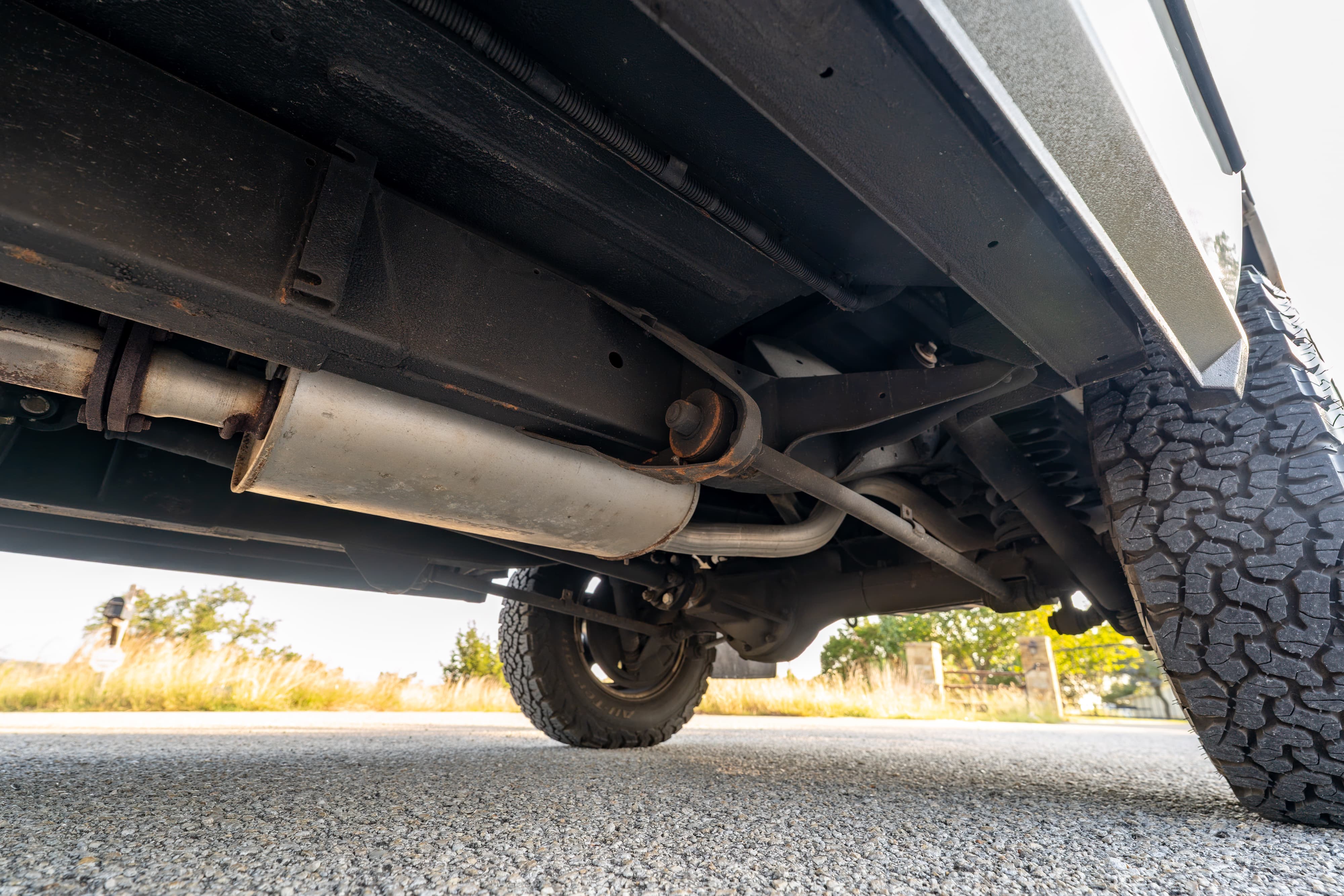 Undercarriage of a white 1995 Land Rover Range Rover County, showing the exhaust system and off-road tires.