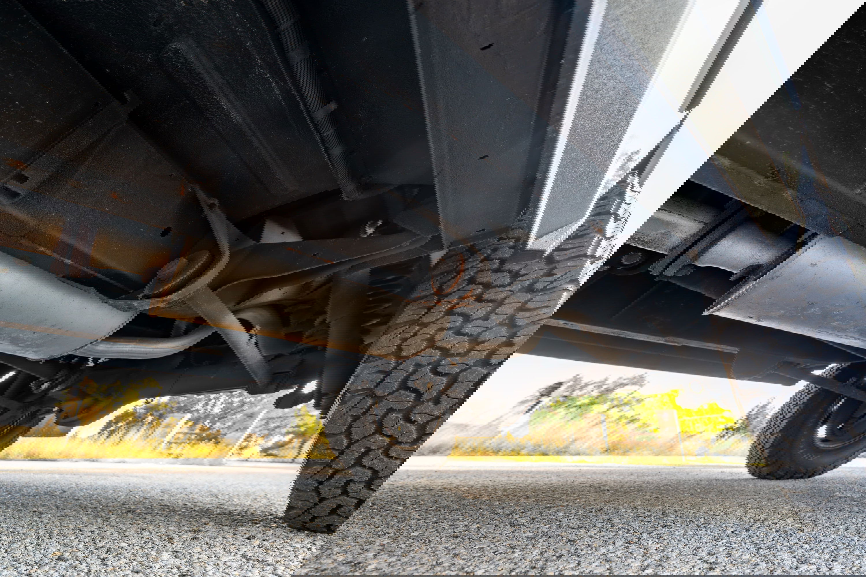 Undercarriage of a white 1995 Land Rover Range Rover County, showing the exhaust system and off-road tires.