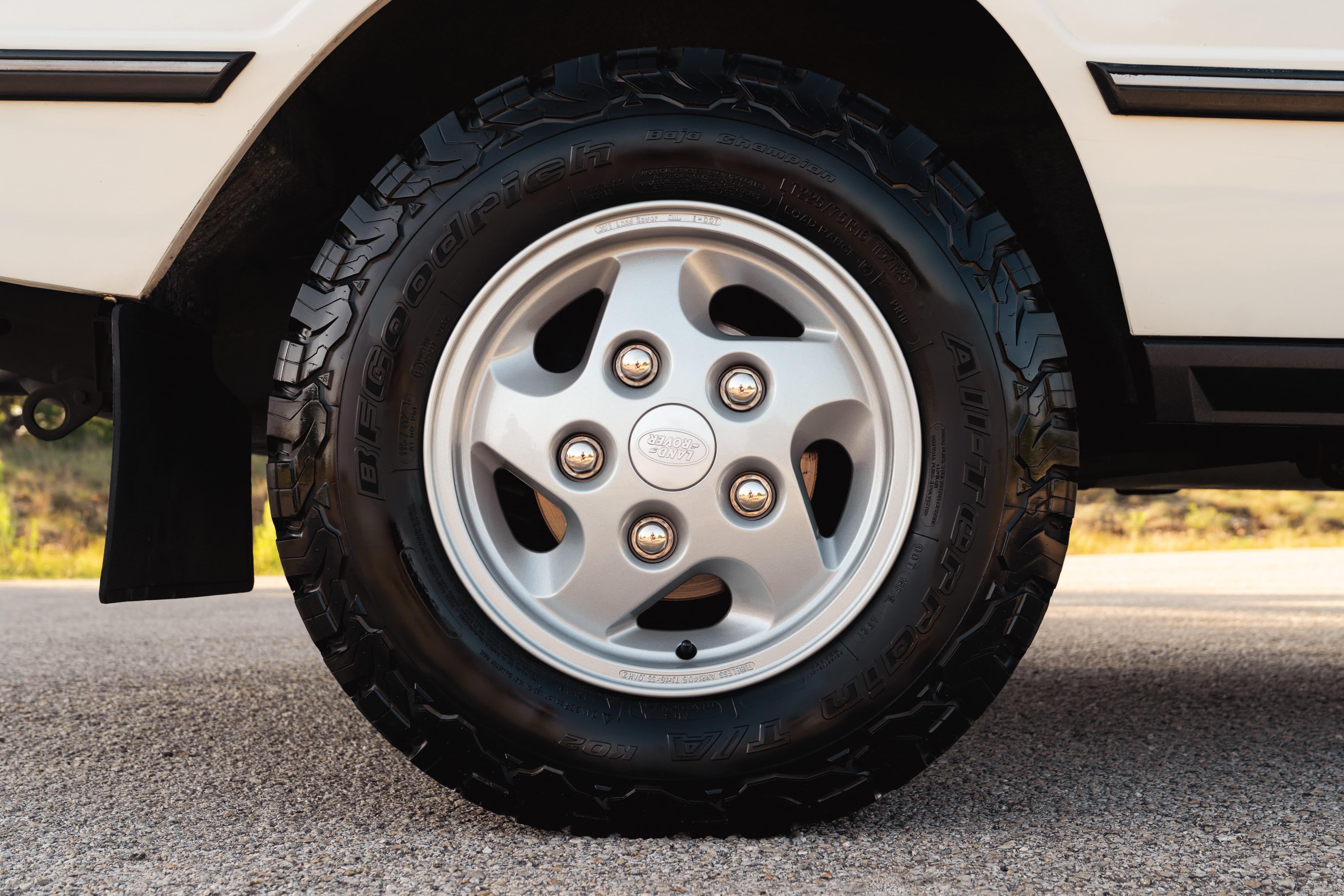 Close-up of a white 1995 Range Rover County's silver 5-spoke alloy rim with BFGoodrich tires.