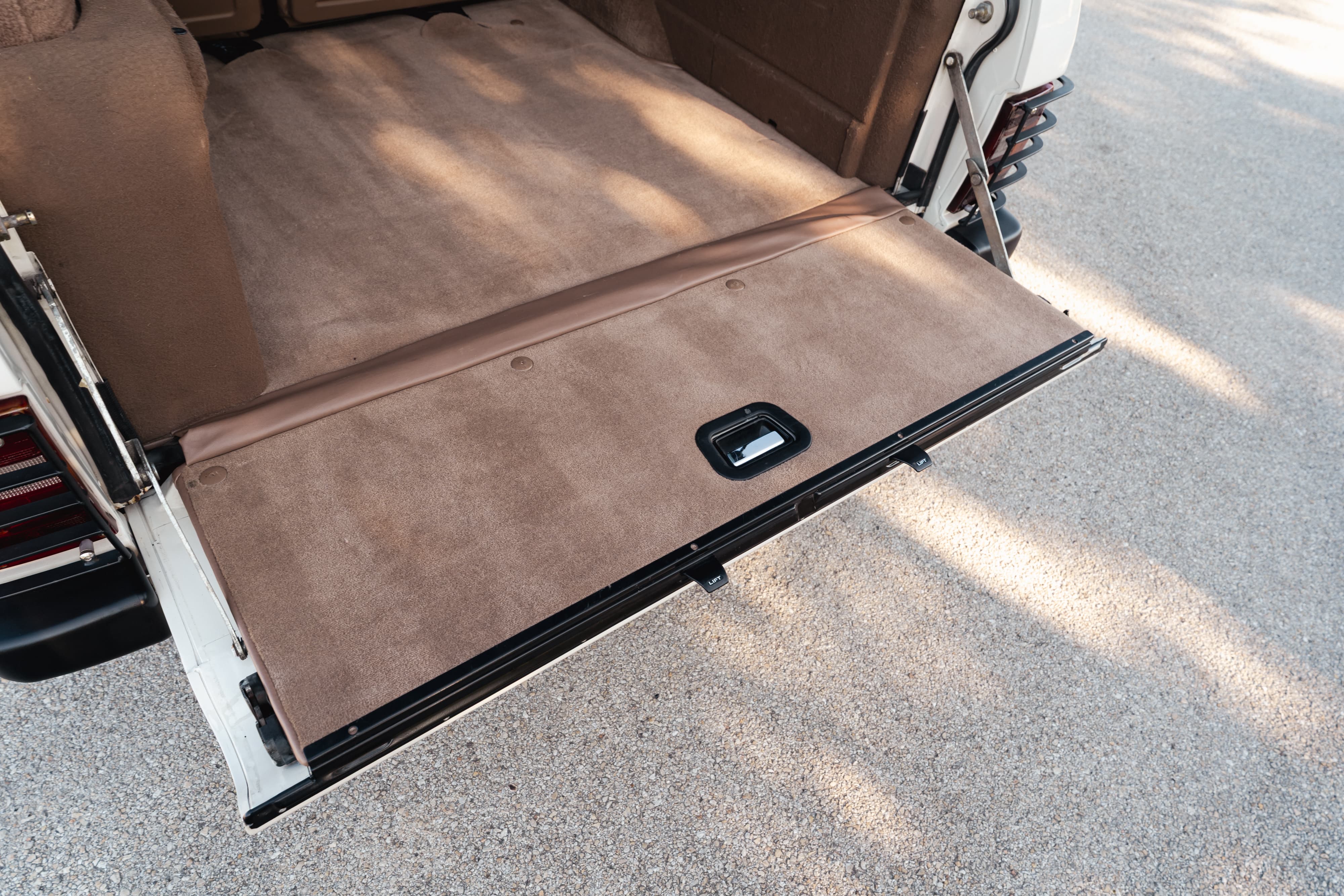 1995 Range Rover County cargo area with tan carpet and lowered tailgate.