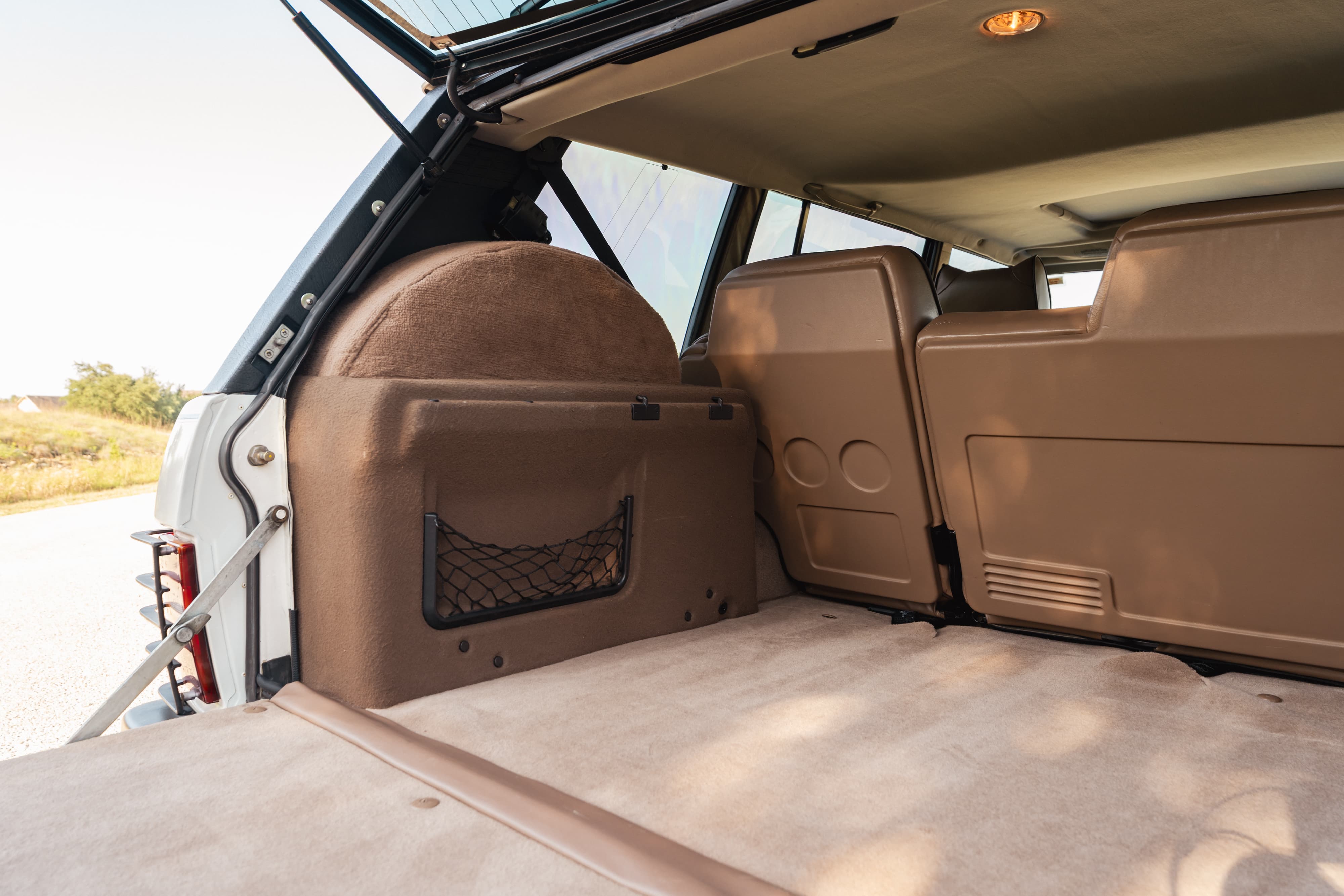 1995 Land Rover Range Rover County interior cargo area. Tan upholstery, carpeted floor, and spare tire cover.