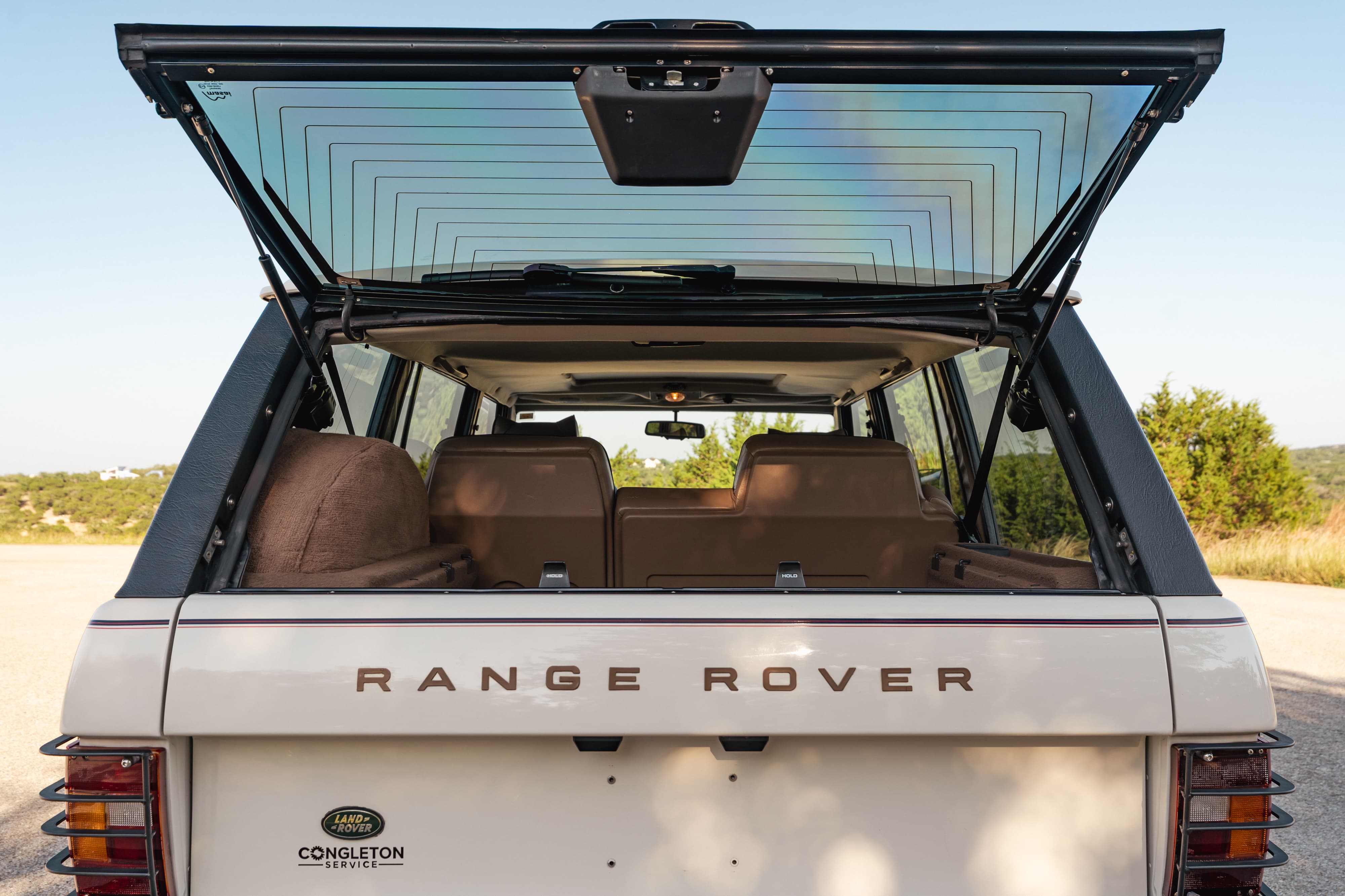 1995 Range Rover County rear hatch open, showing tan interior, chrome badge and trim.