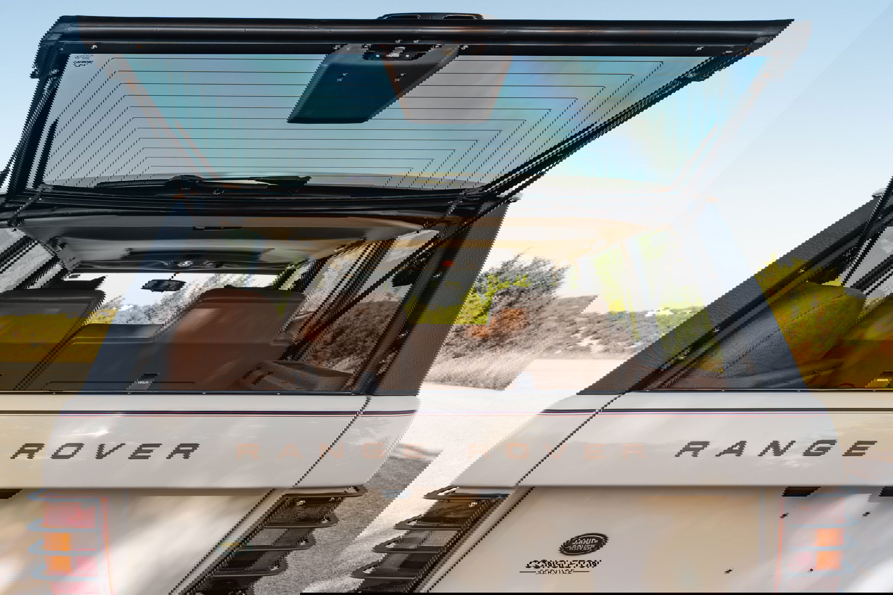 1995 Range Rover County rear hatch open, showing tan interior, chrome badge and trim.