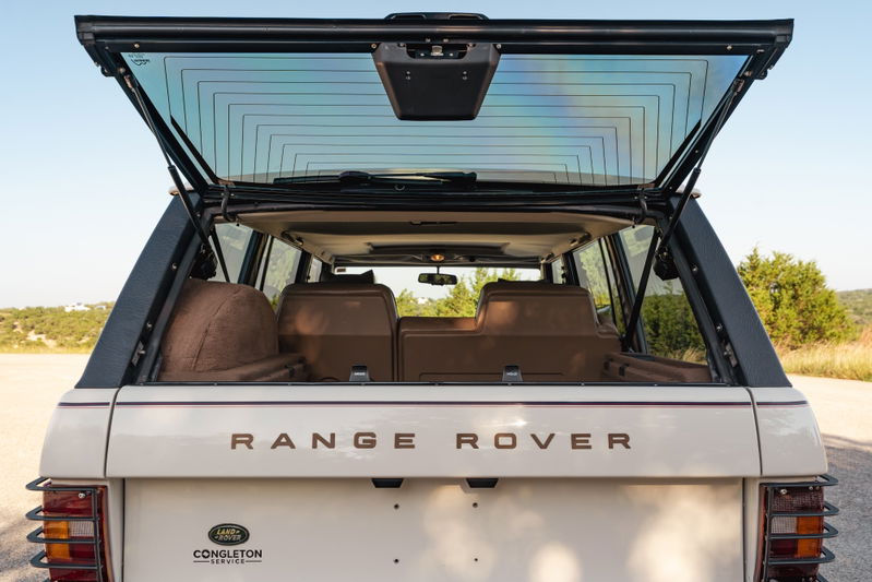 1995 Range Rover County rear hatch open, showing tan interior, chrome badge and trim.