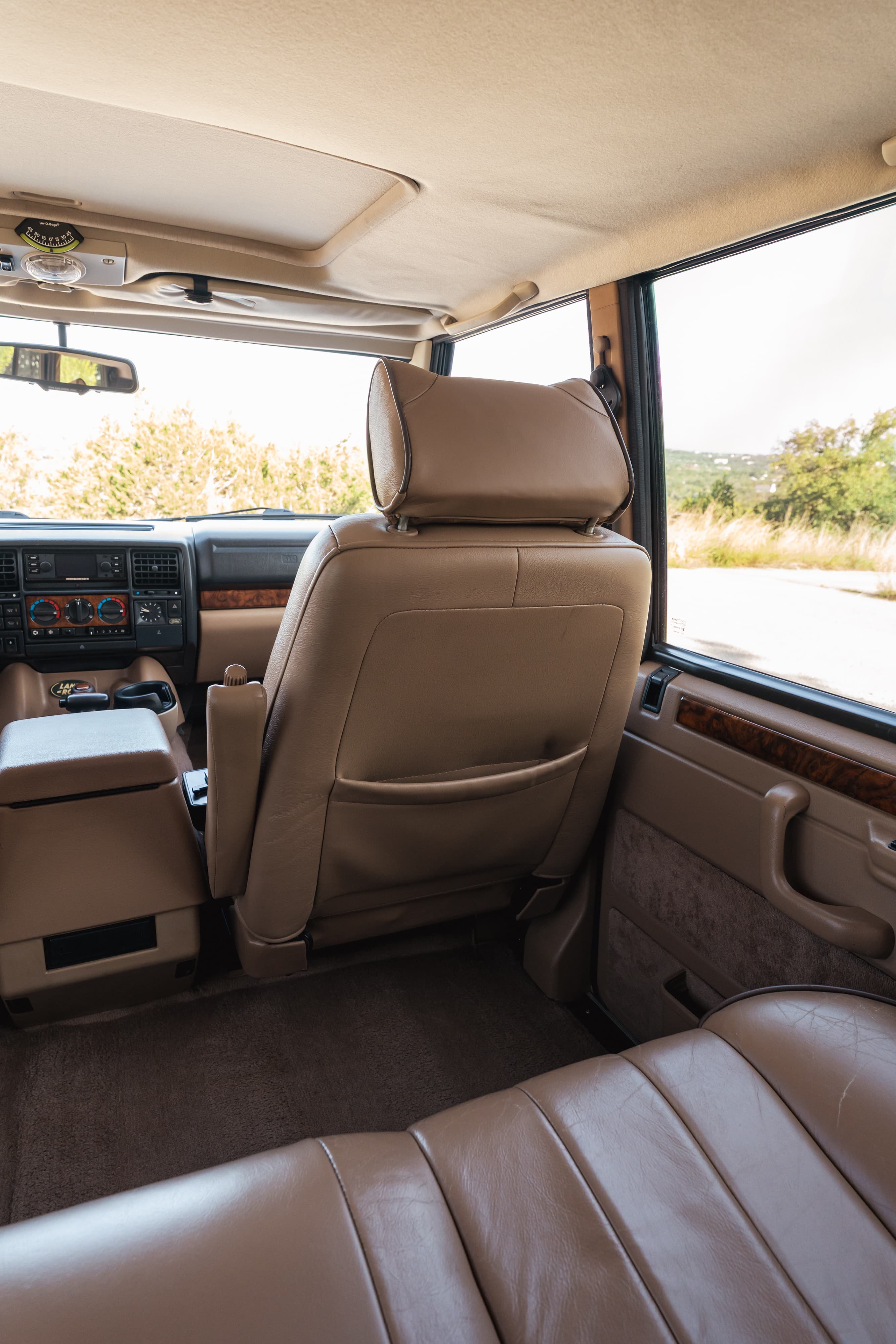 Interior of a white 1995 Land Rover Range Rover County, featuring tan leather seats and wood trim.