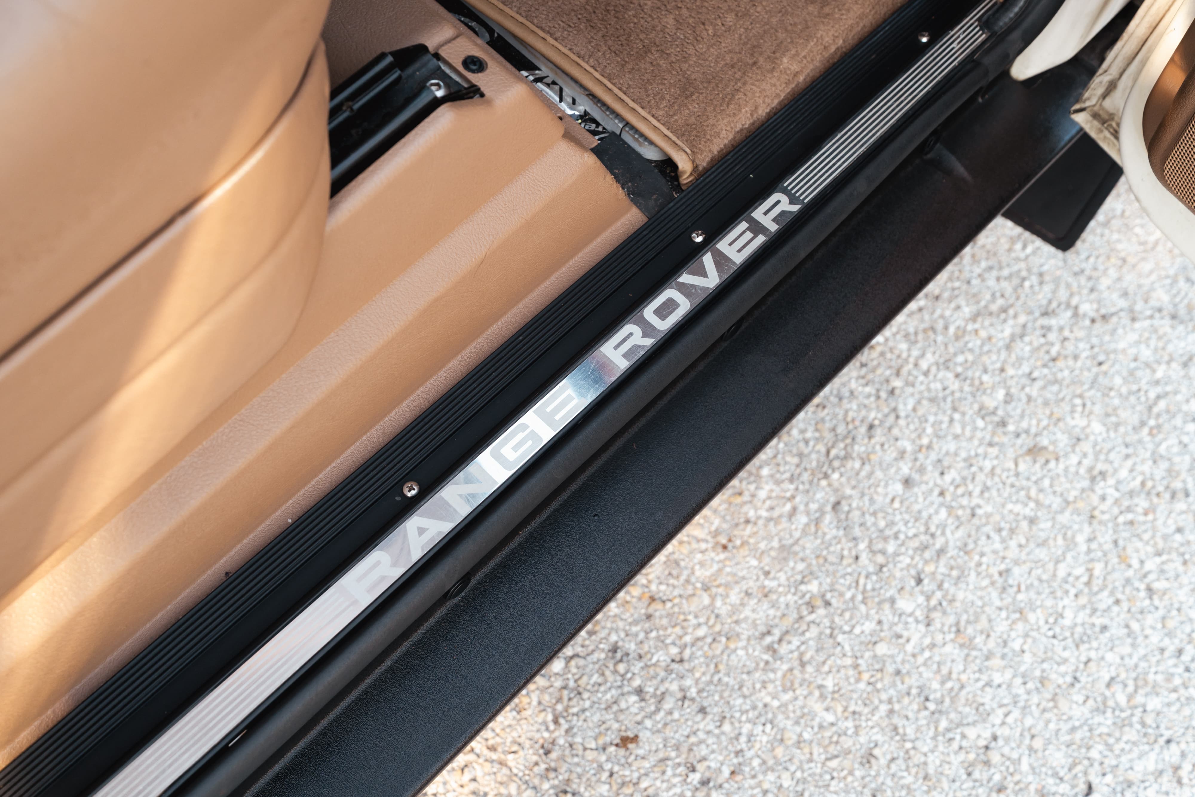 Close-up of the Range Rover lettering on the door sill trim of a white 1995 Land Rover Range Rover County.