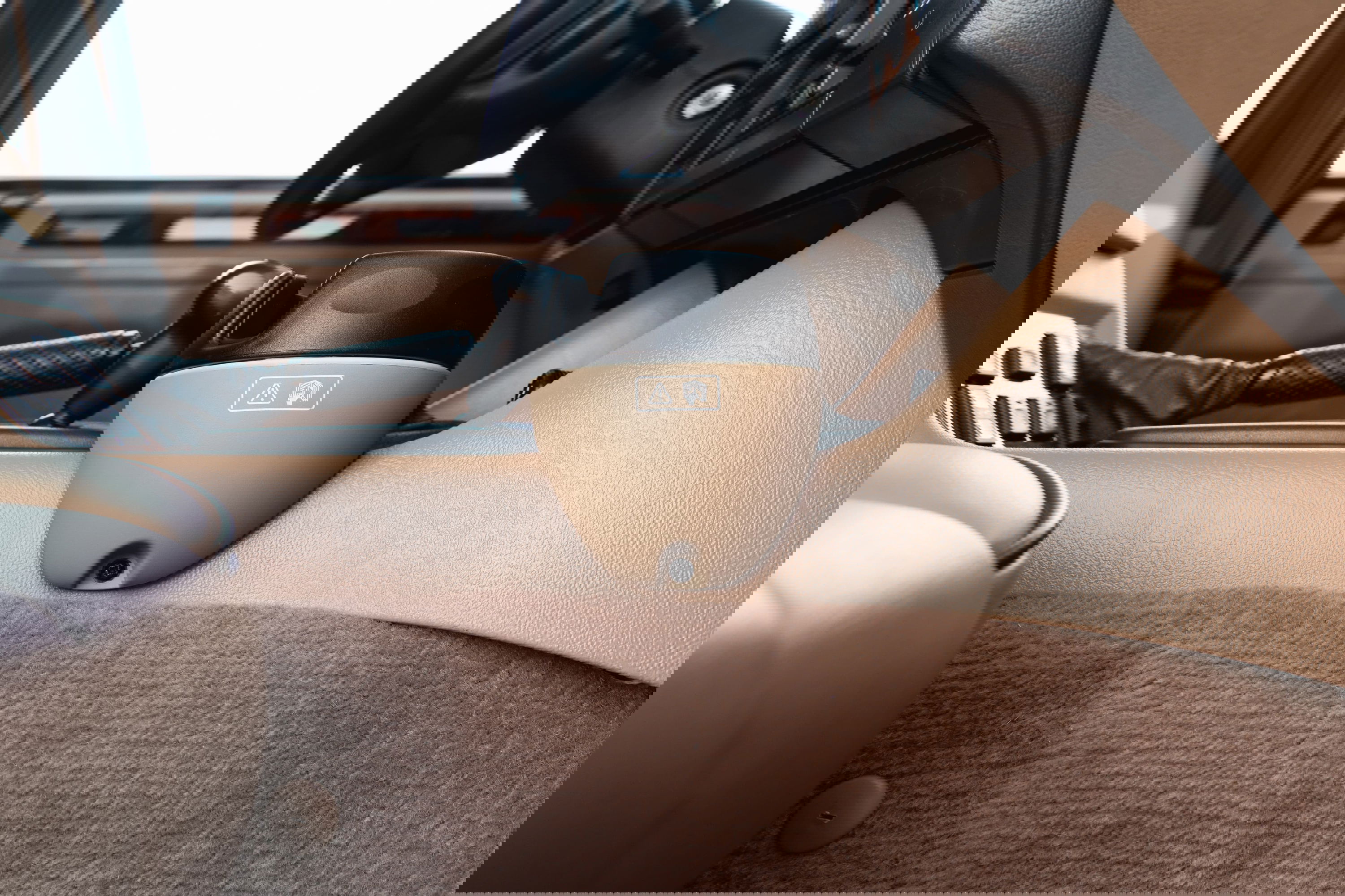 Interior of a white 1995 Land Rover Range Rover County, showing the tan dashboard, floor mats, and center console with cup holder.