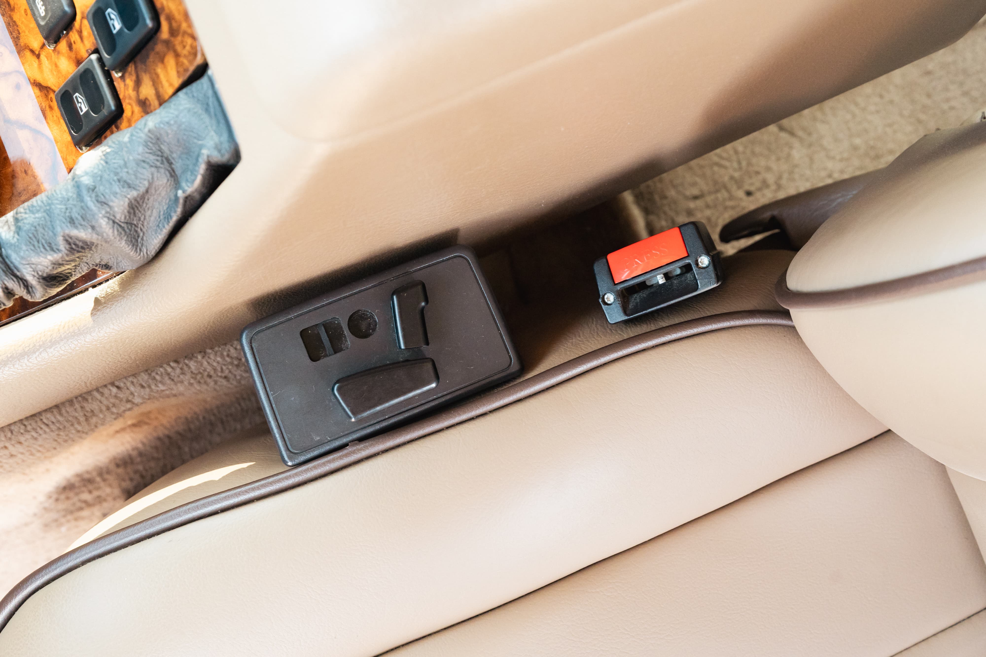 1995 Land Rover Range Rover County interior: tan leather seats, wood trim, seat belt buckle, and seat controls.