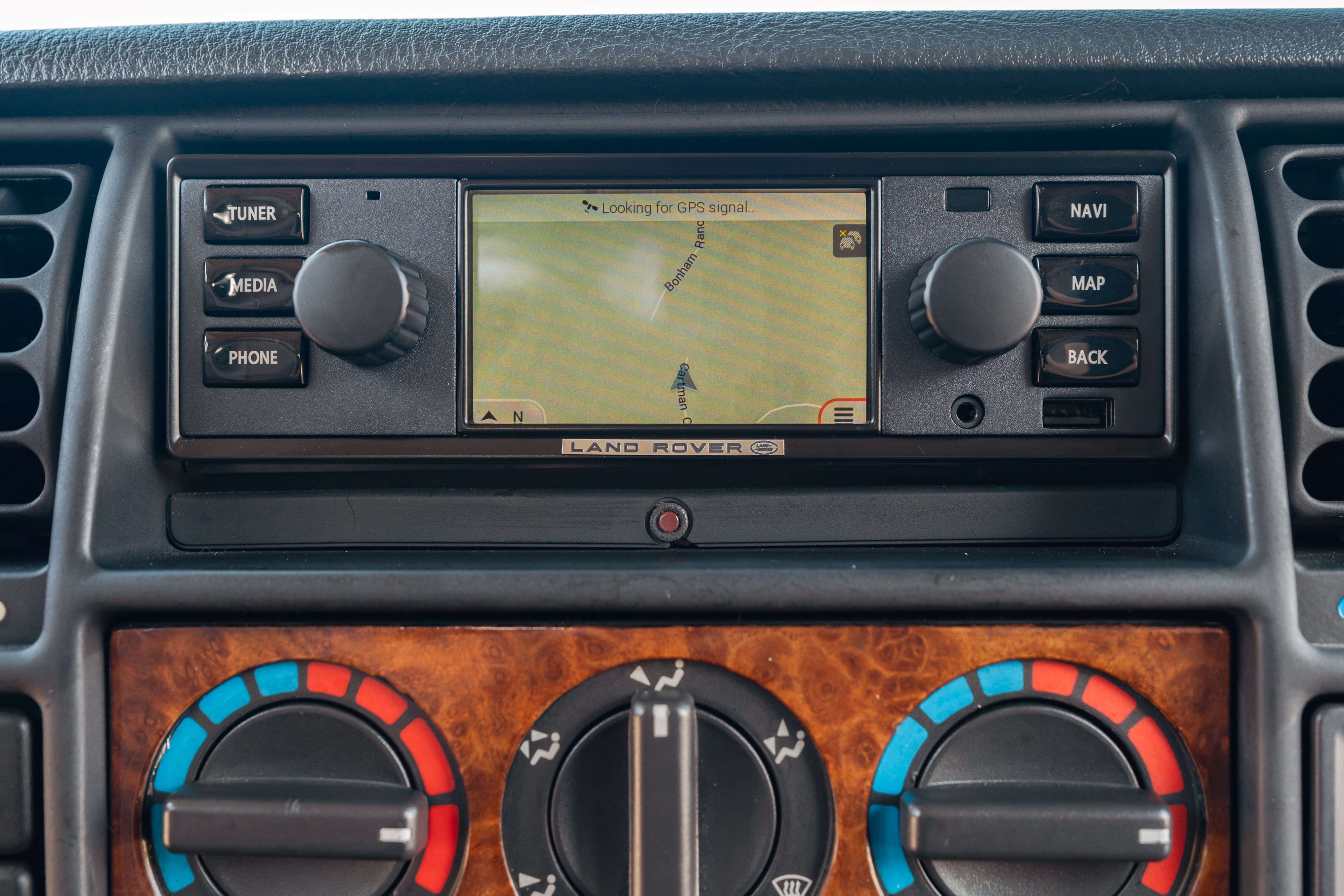 1995 white Land Rover Range Rover County dashboard with navigation screen and wood trim.
