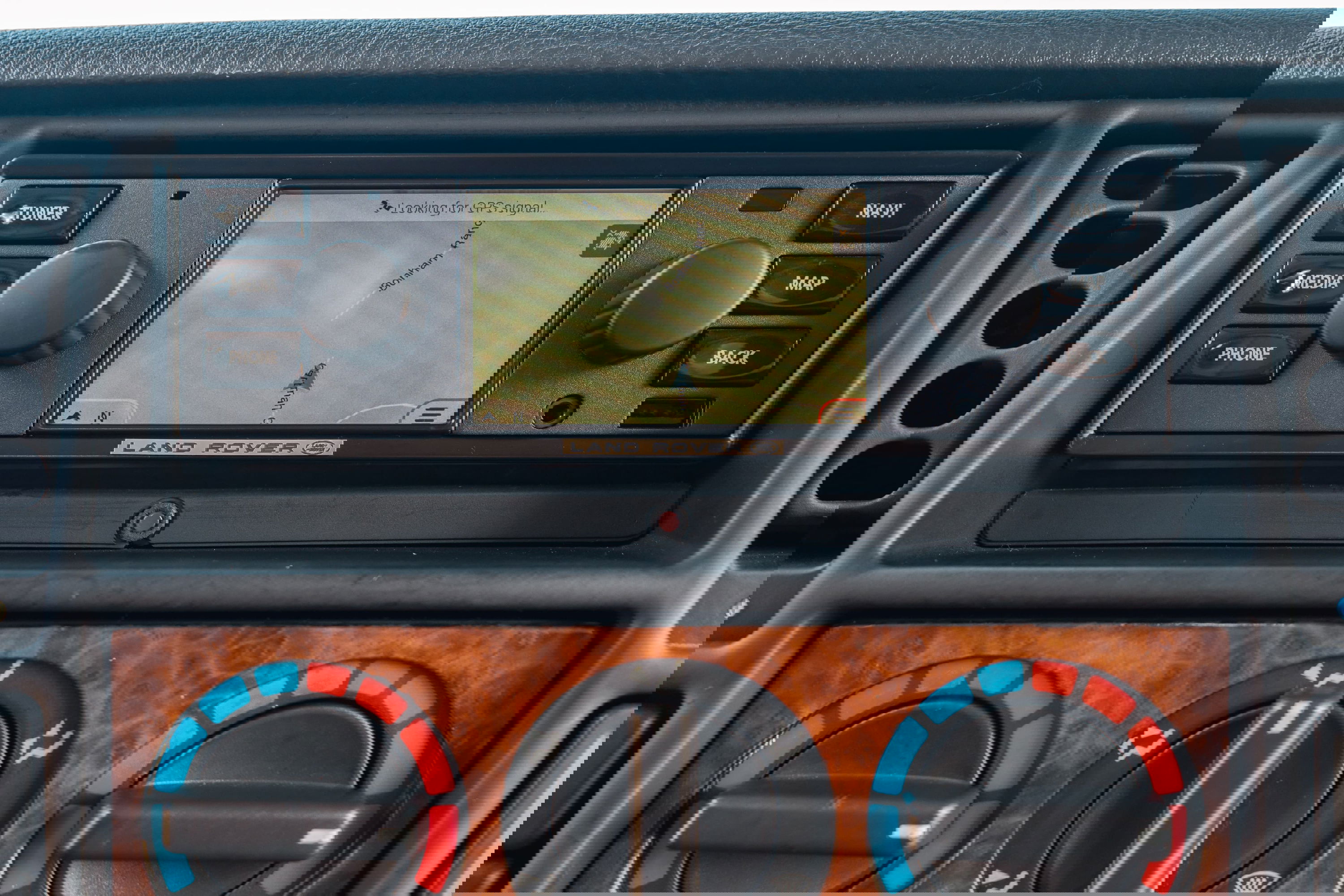 1995 white Land Rover Range Rover County dashboard with navigation screen and wood trim.