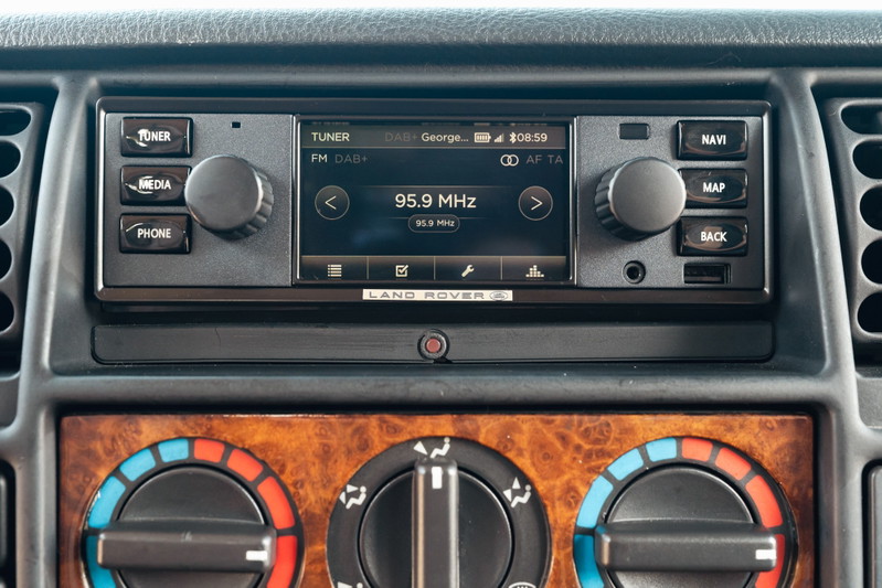 Interior of a white 1995 Land Rover Range Rover County, showing the dashboard infotainment system and climate controls.