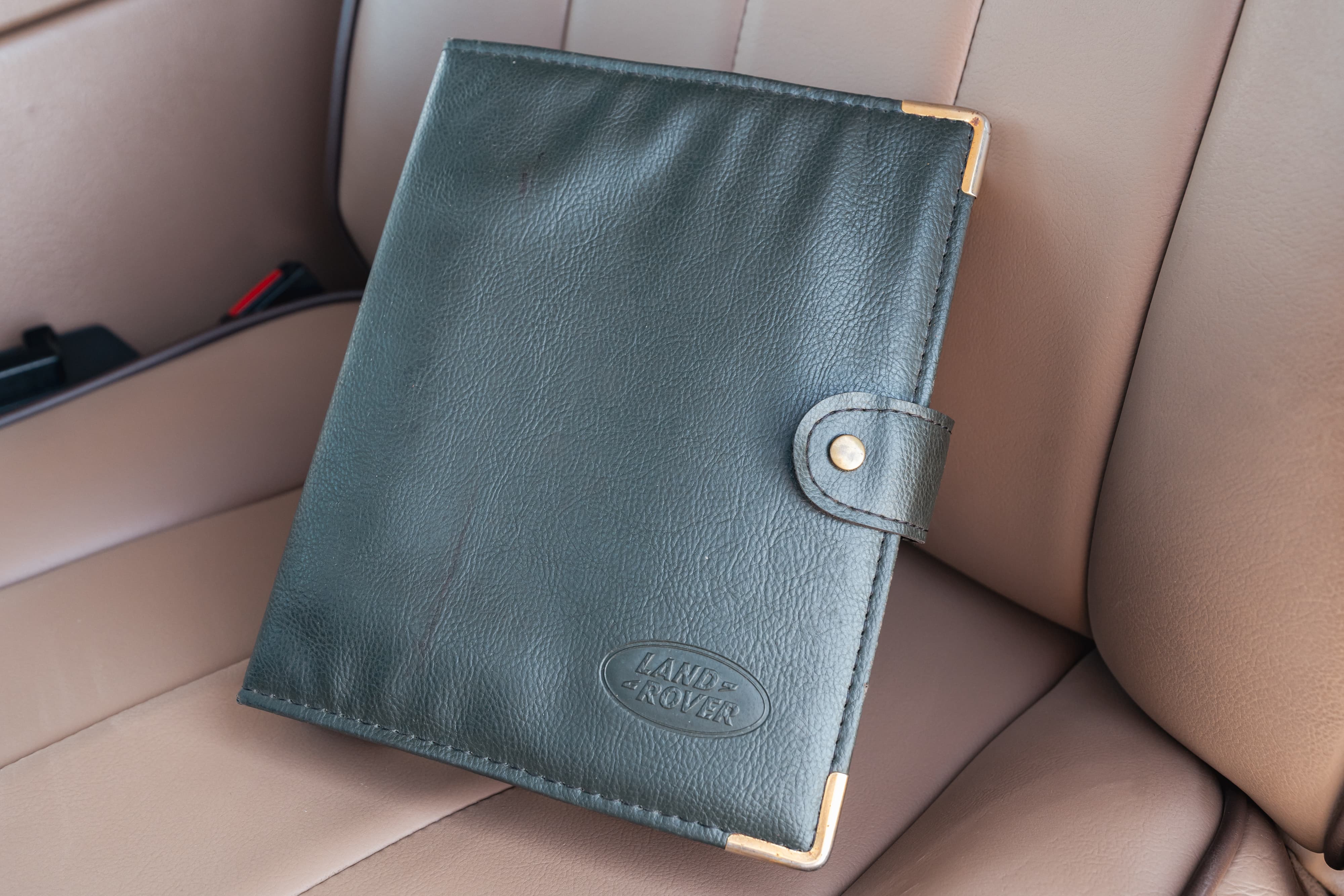 Black leather Land Rover owner's manual with gold trim, inside a 1995 Range Rover County.