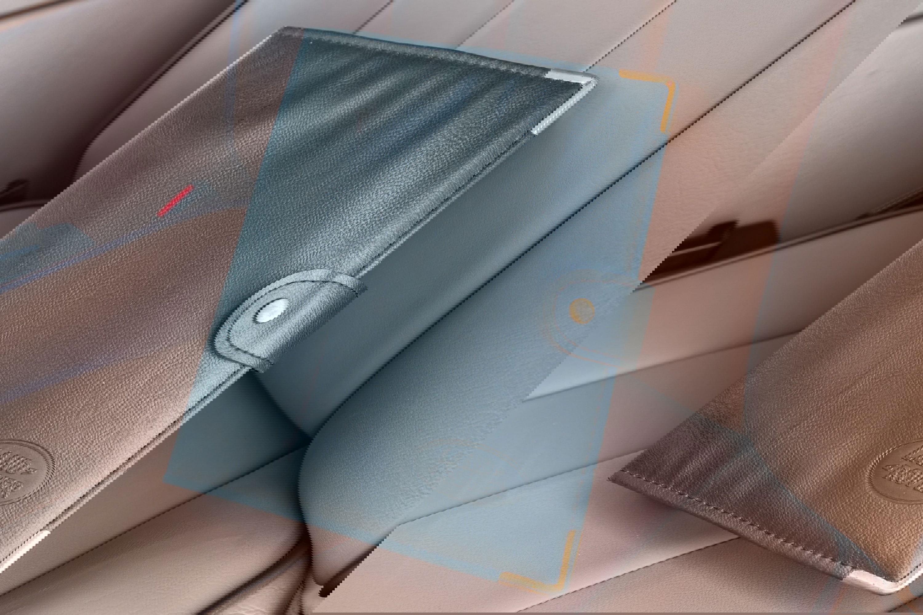 Black leather Land Rover owner's manual with gold trim, inside a 1995 Range Rover County.