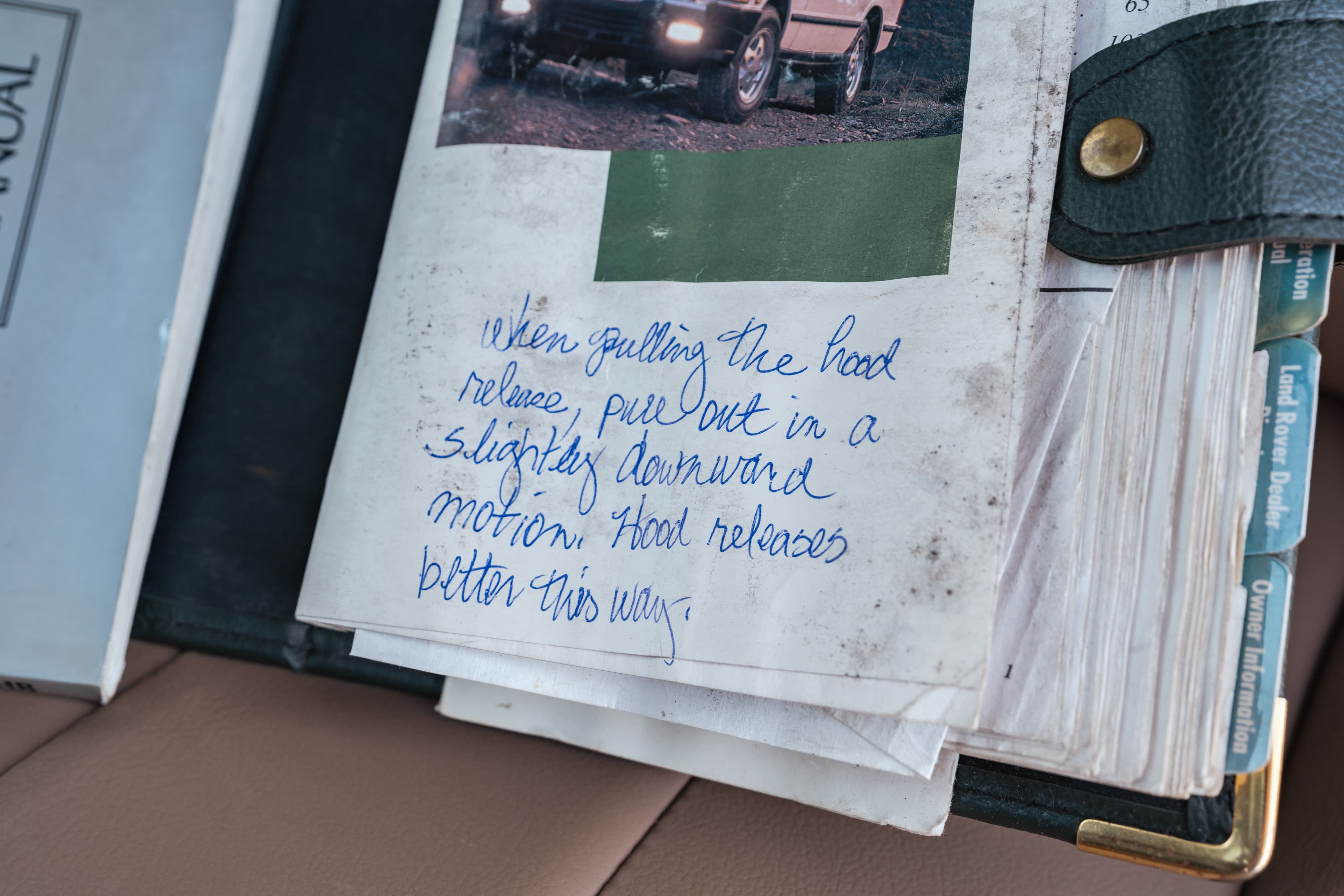 White 1995 Land Rover Range Rover County owner's manual with handwritten hood release instructions.