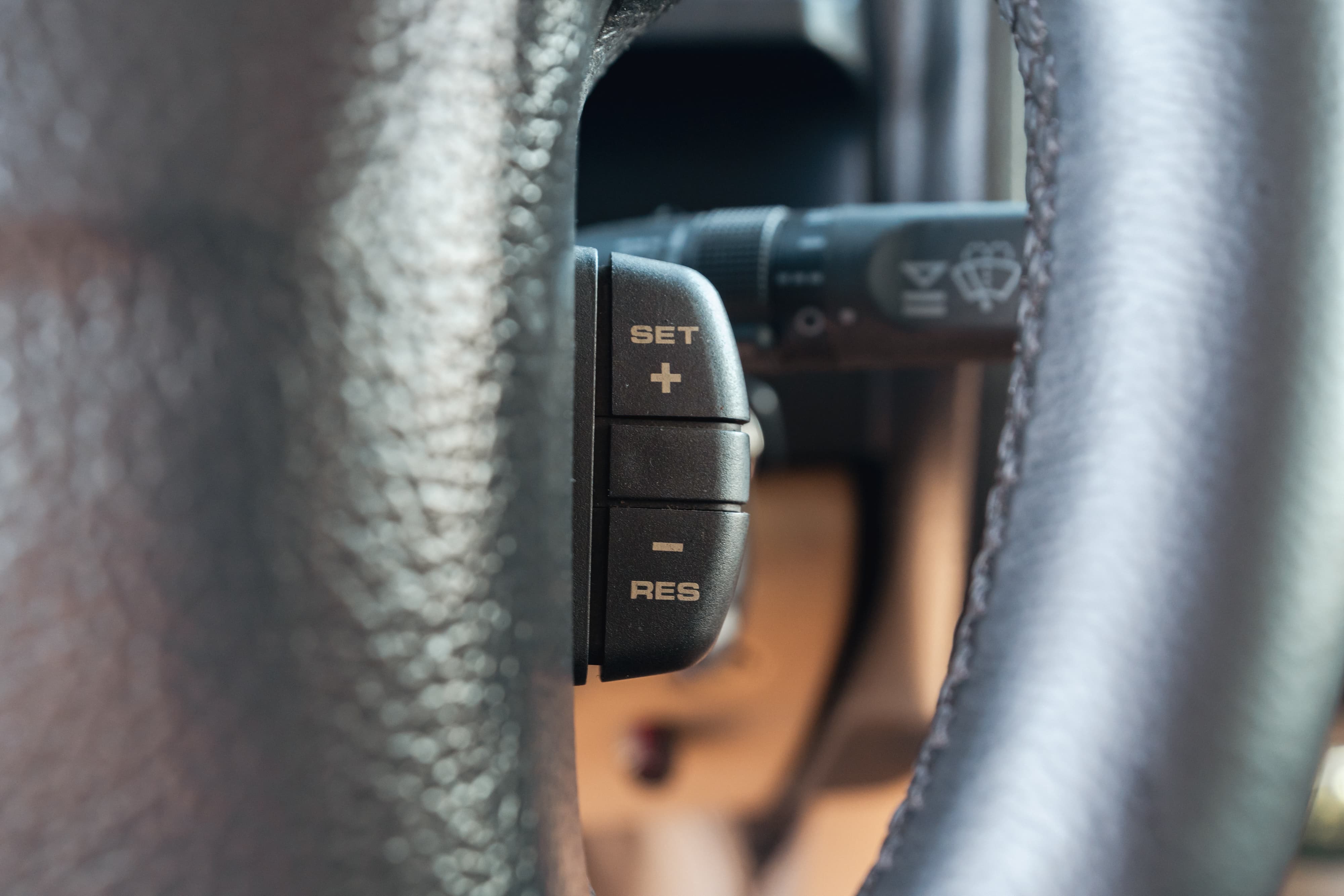 Close-up of a black cruise control stalk on the steering wheel of a white 1995 Land Rover Range Rover County.