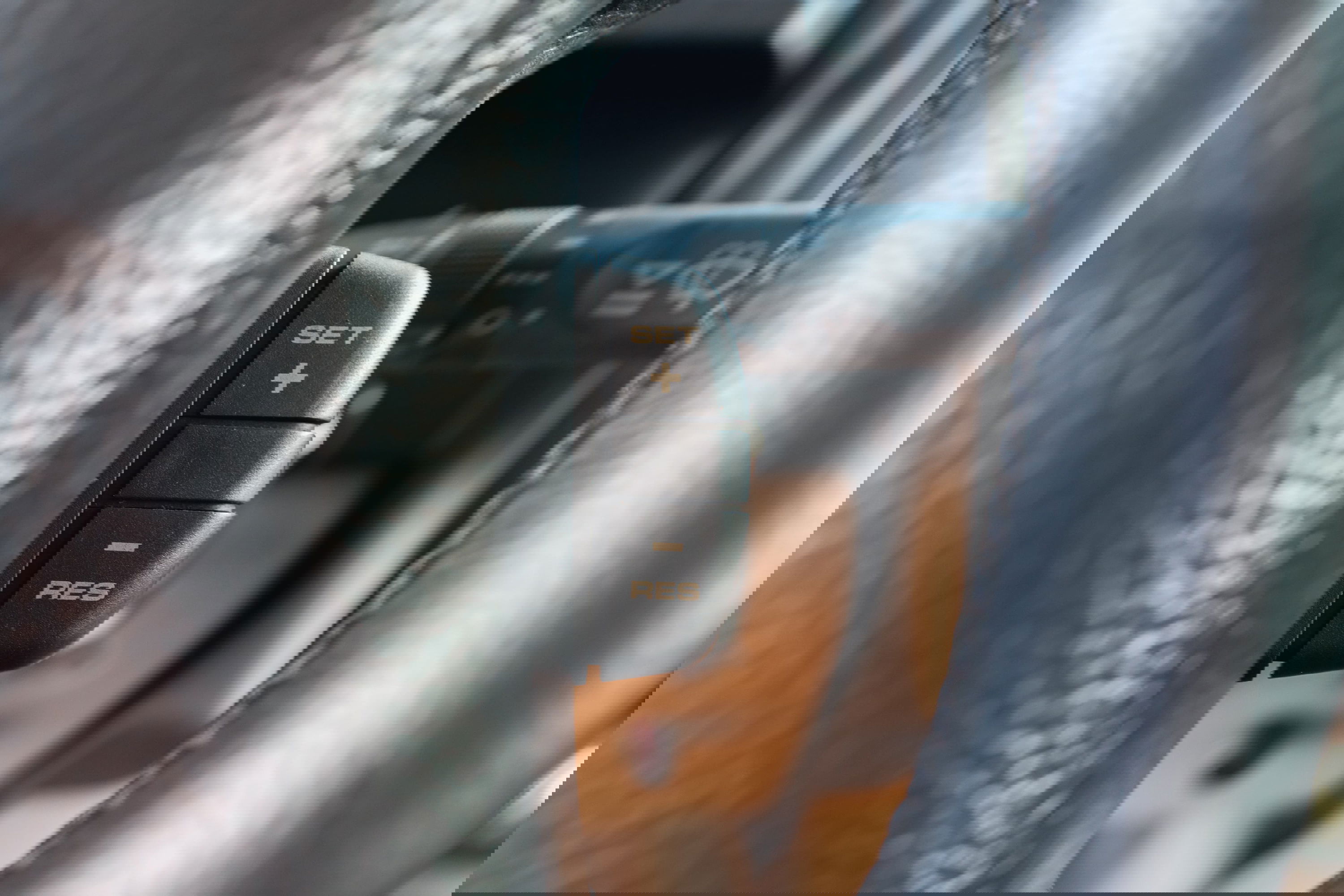 Close-up of a black cruise control stalk on the steering wheel of a white 1995 Land Rover Range Rover County.