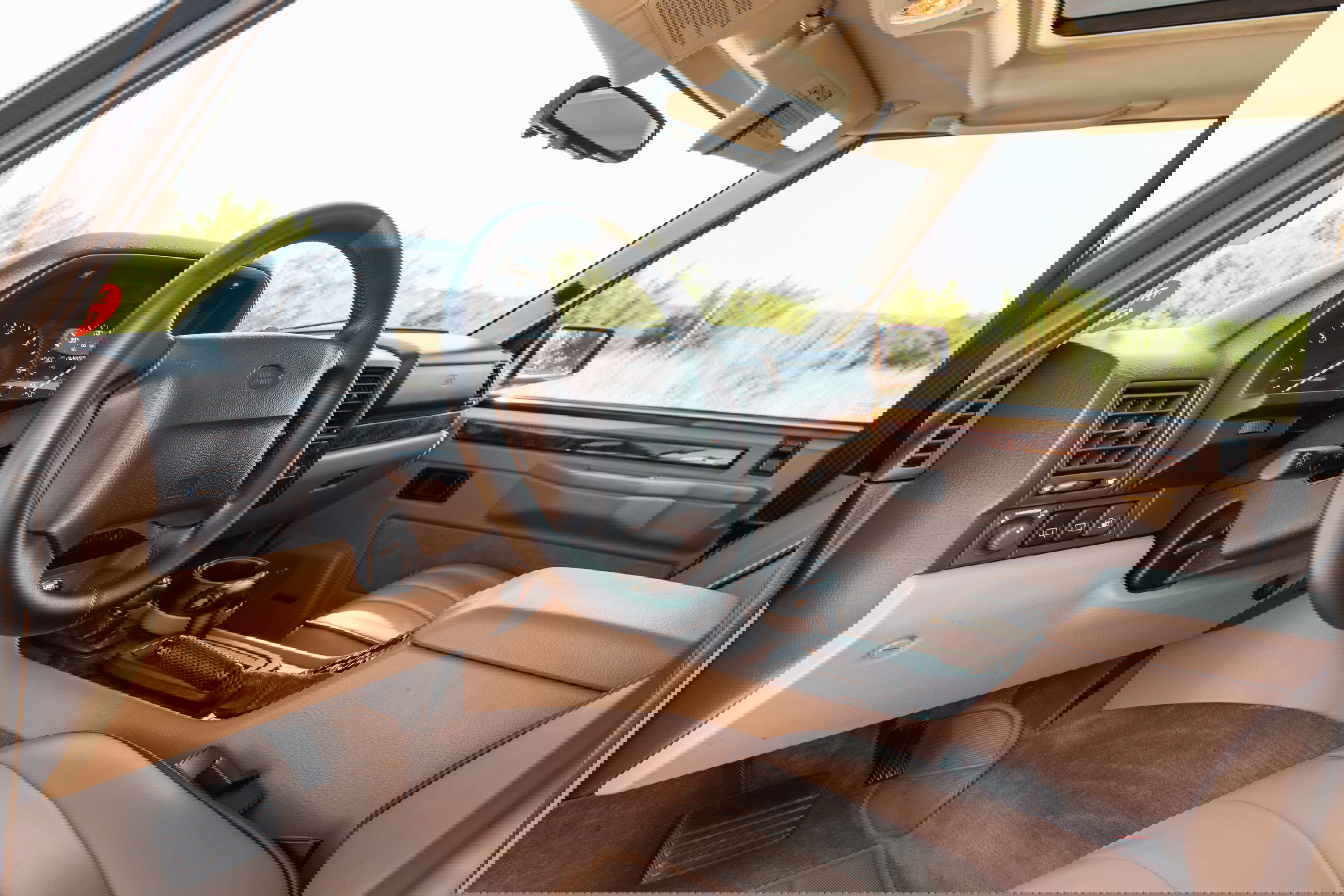 Interior of a white 1995 Land Rover Range Rover County, showing the dashboard, steering wheel, and tan leather seats.