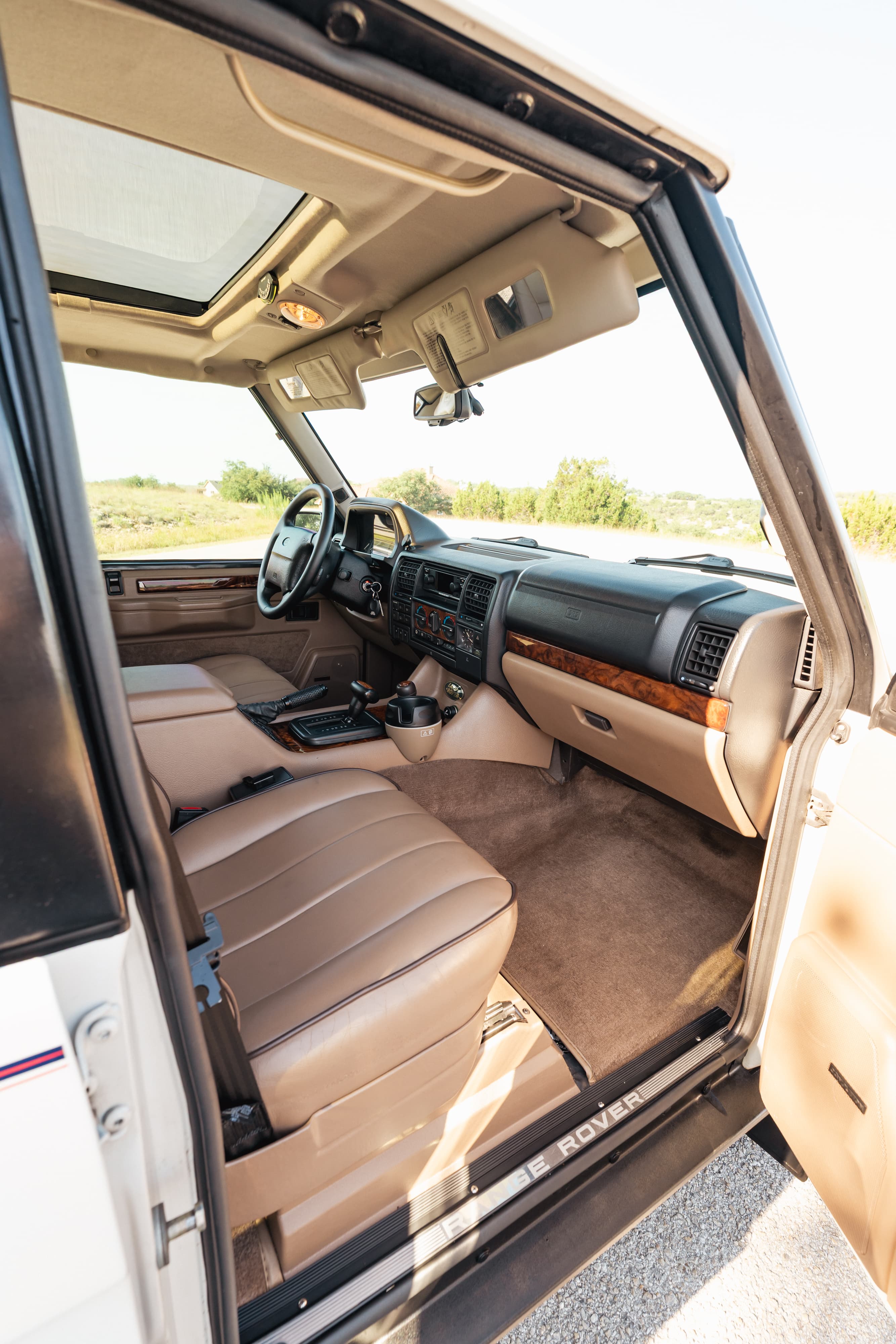 1995 Range Rover County interior in tan leather with wood trim, sunroof, and Range Rover door sills.