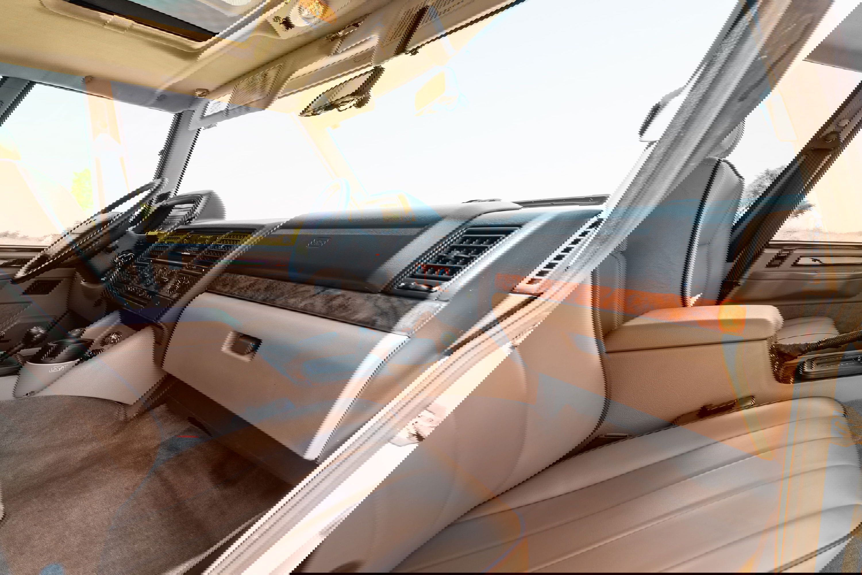 Interior view of a white 1995 Range Rover County, showcasing tan leather seats and wood trim.