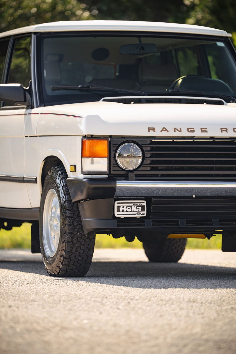 White 1995 Range Rover County front grille with Hella badge and chrome rims.