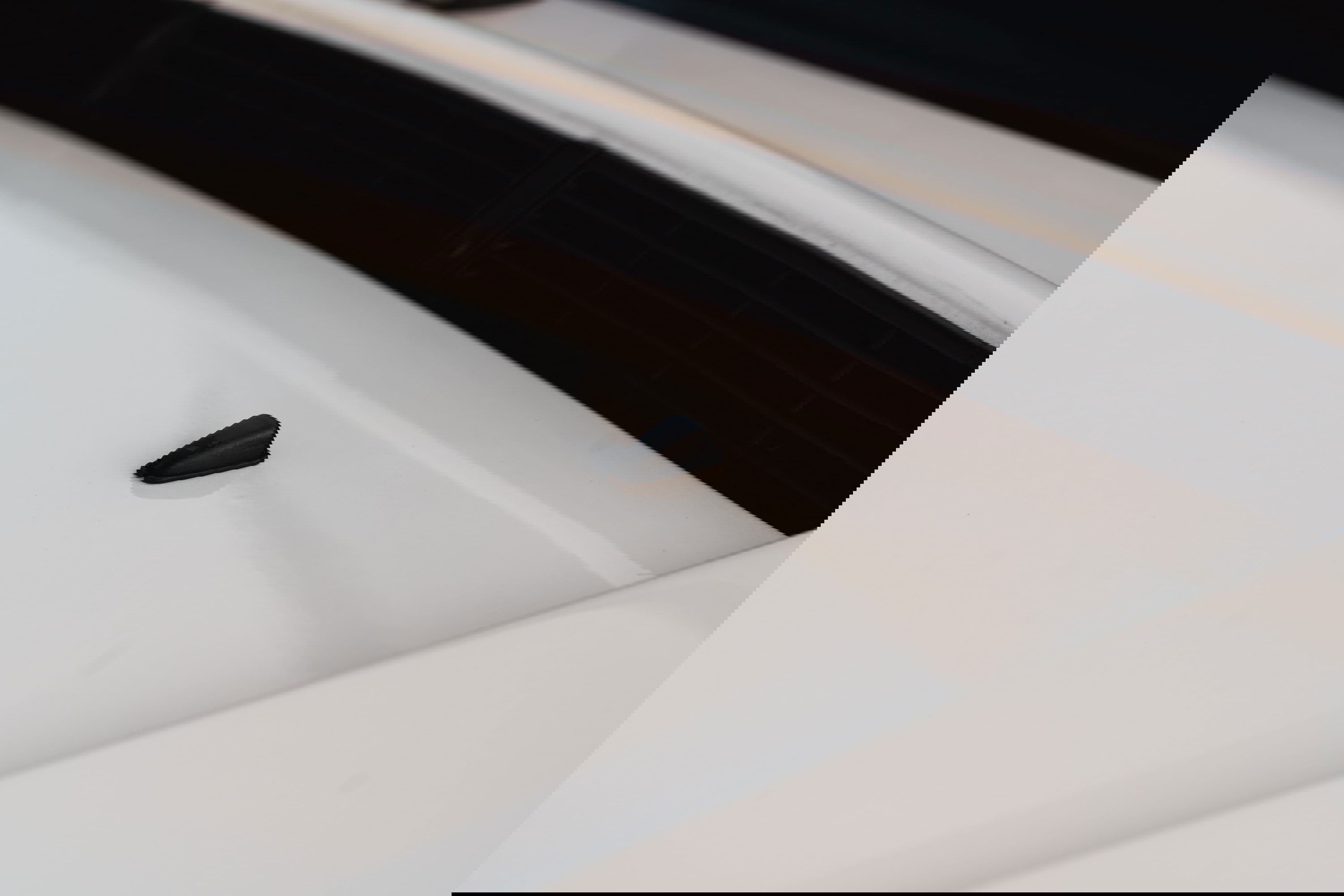 Black windshield washer nozzle on the hood of a white 1995 Land Rover Range Rover County.