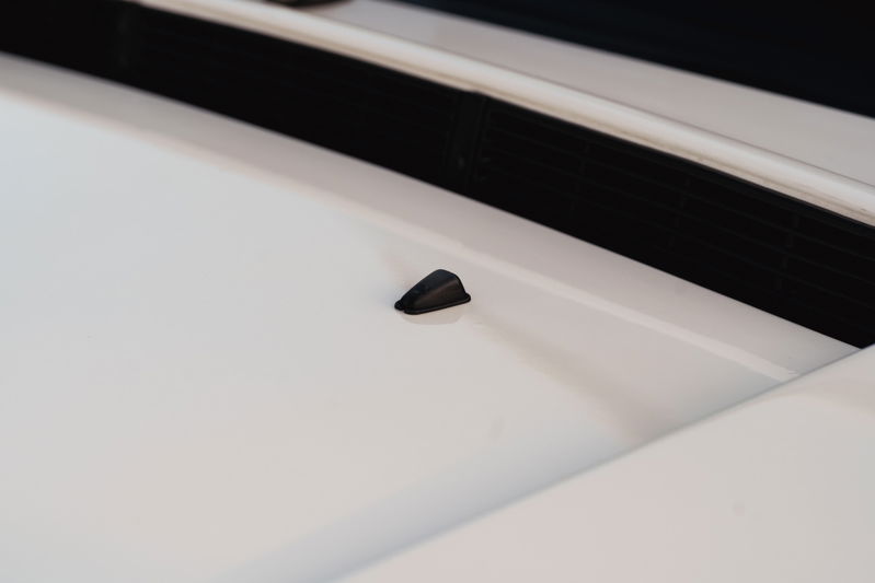 Black windshield washer nozzle on the hood of a white 1995 Land Rover Range Rover County.