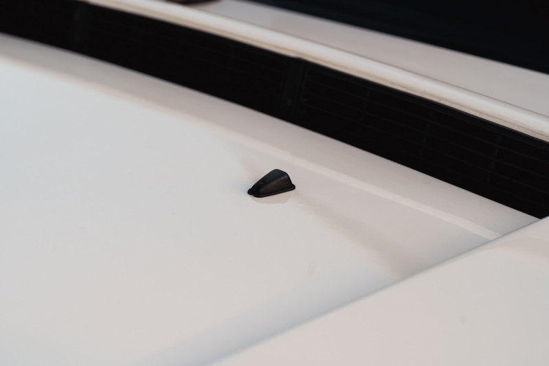 Black windshield washer nozzle on the hood of a white 1995 Land Rover Range Rover County.