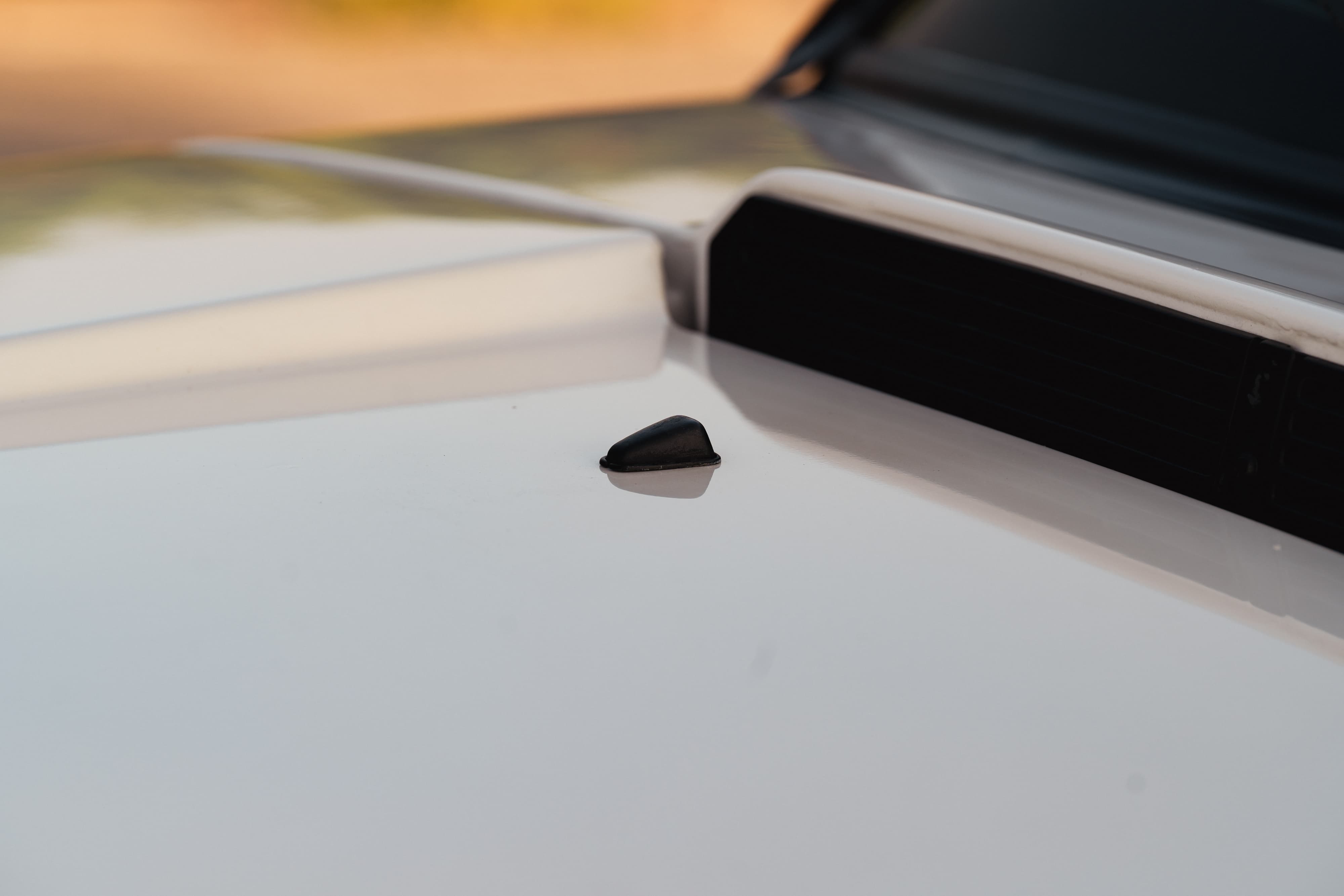 Close-up of a black shark fin antenna on the white roof of a 1995 Land Rover Range Rover County.