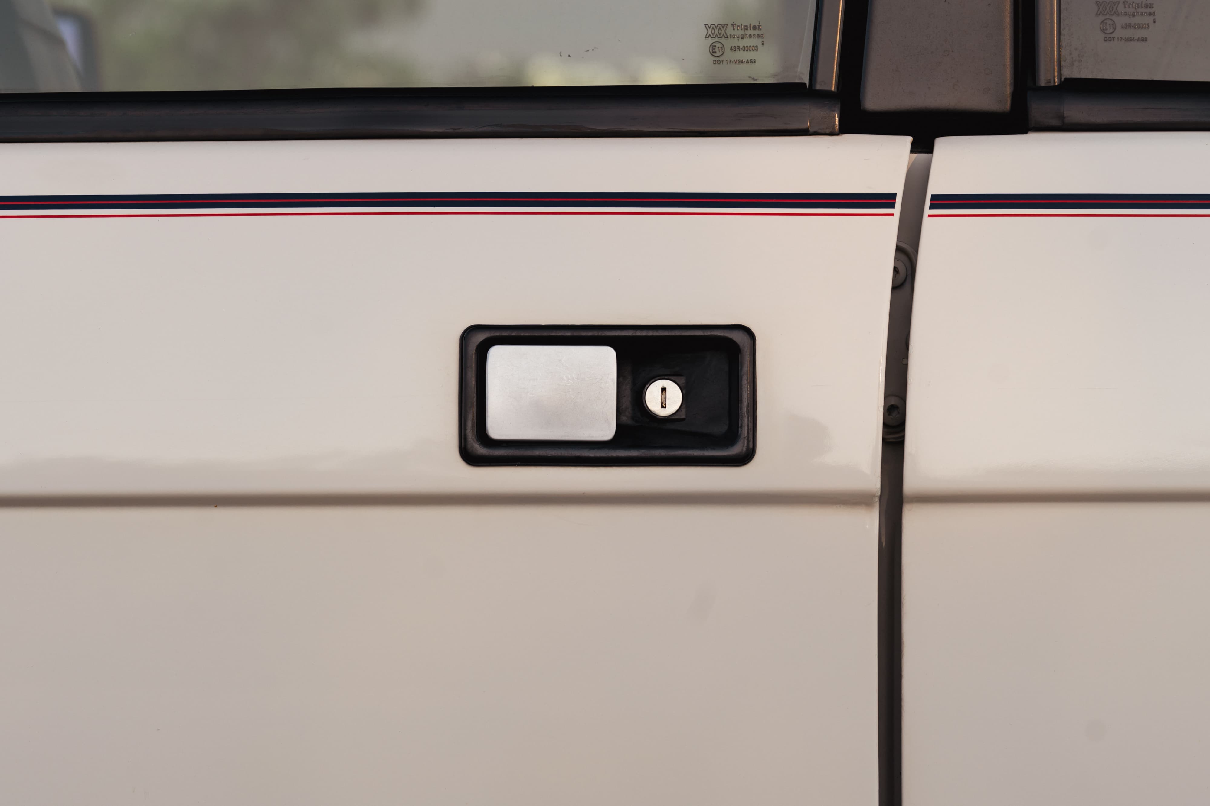 Closeup of a white 1995 Land Rover Range Rover County door handle and body trim.