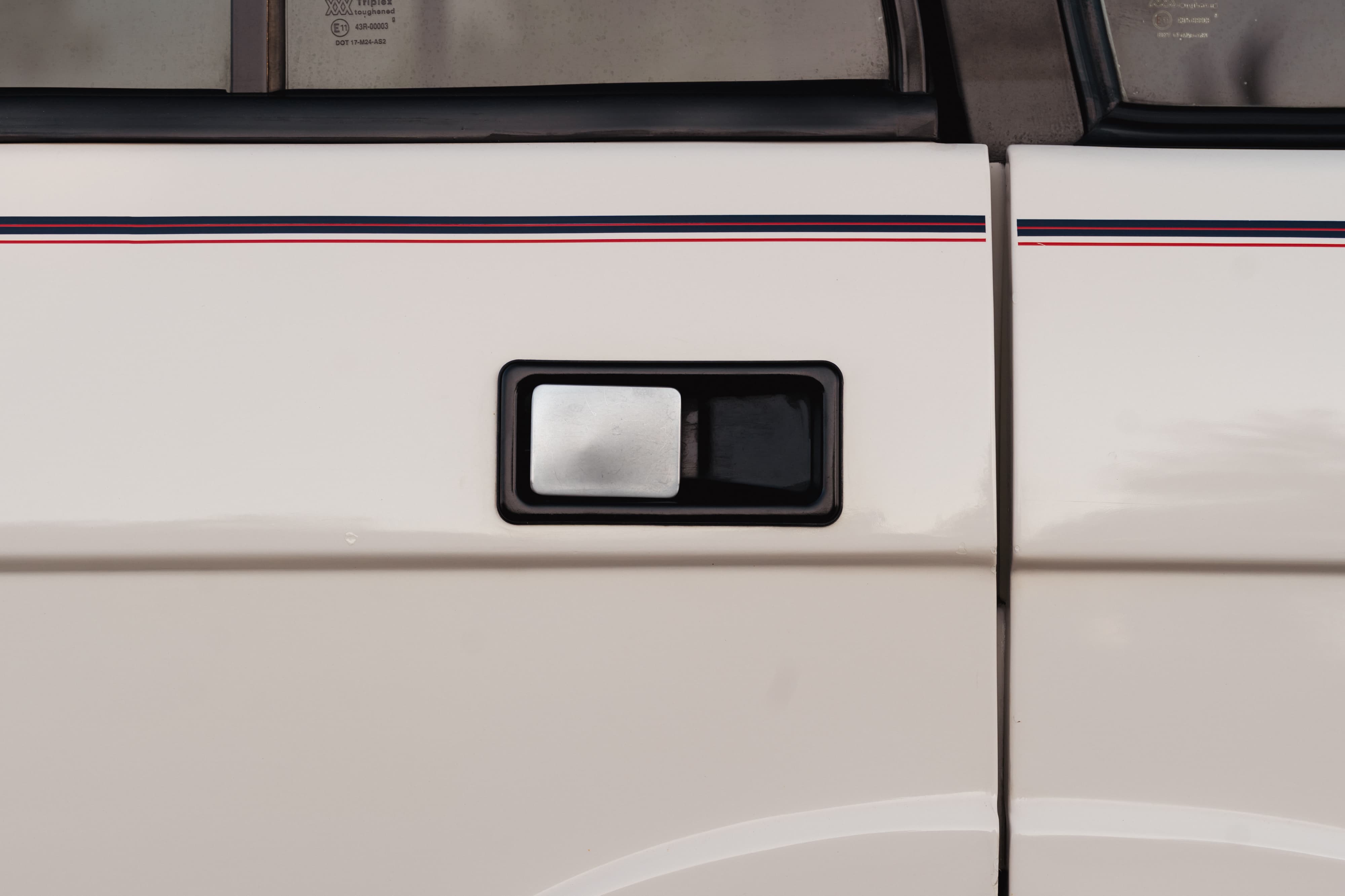 White 1995 Range Rover County with red and blue stripe livery, black and chrome door handle detail.