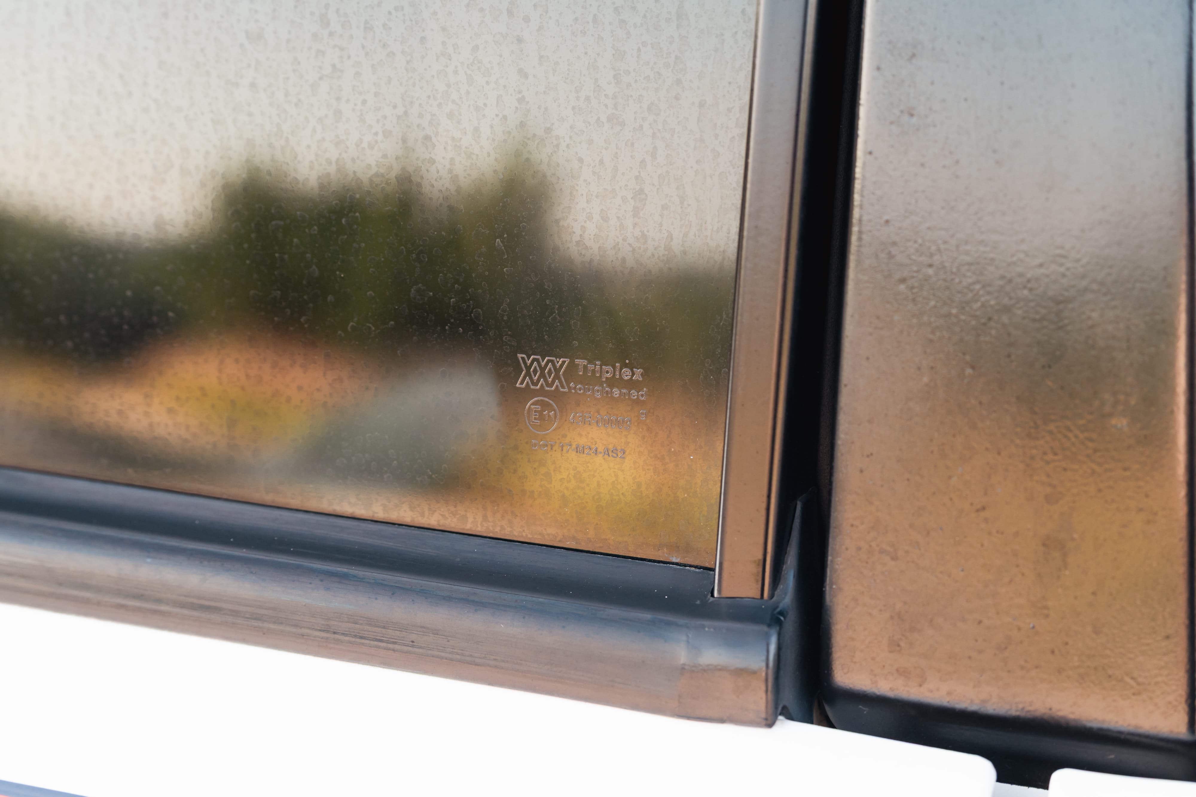 Close-up of the Triplex branded window glass on a white 1995 Land Rover Range Rover County.