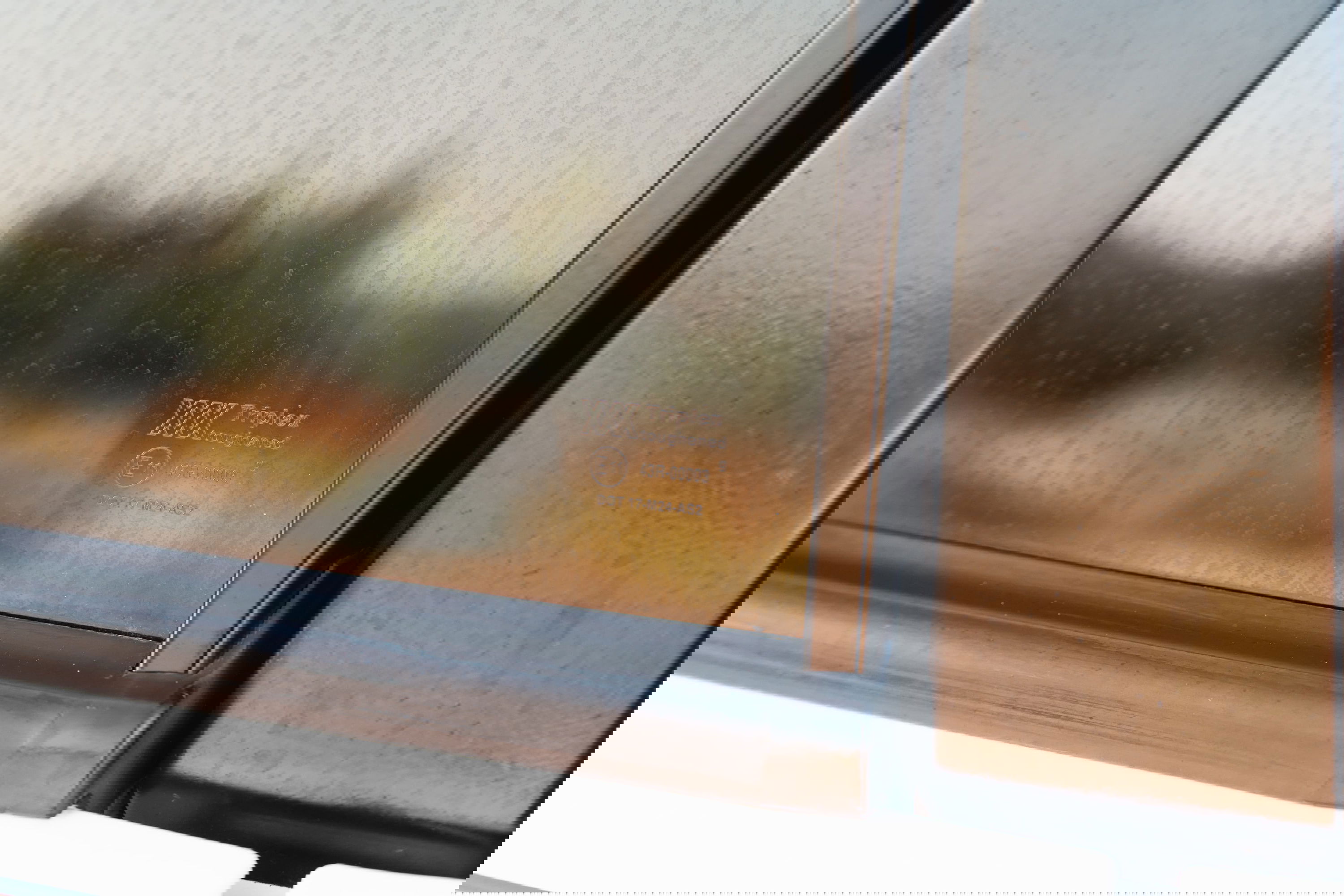 Close-up of the Triplex branded window glass on a white 1995 Land Rover Range Rover County.